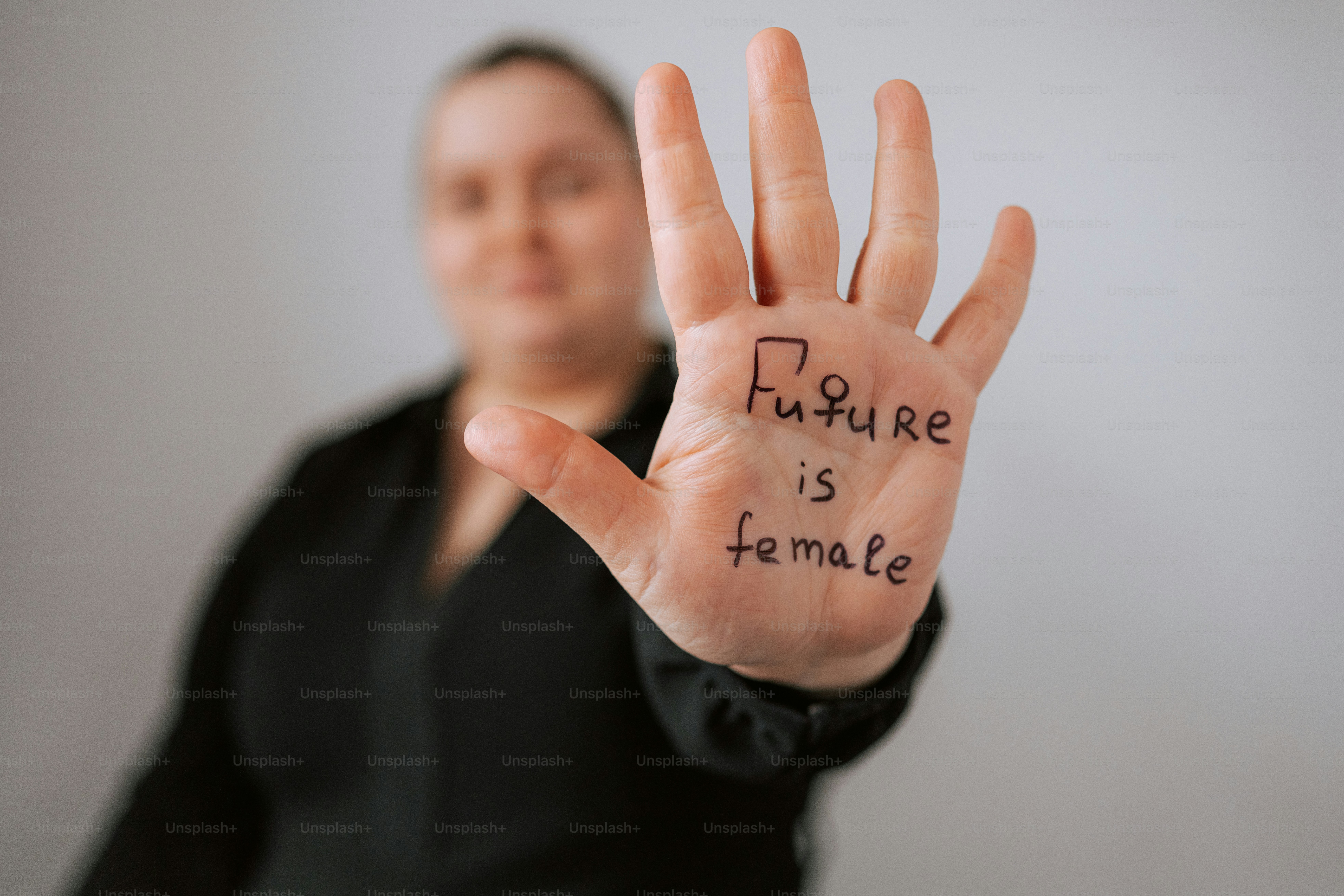 Woman holds hand with "future is female" written.