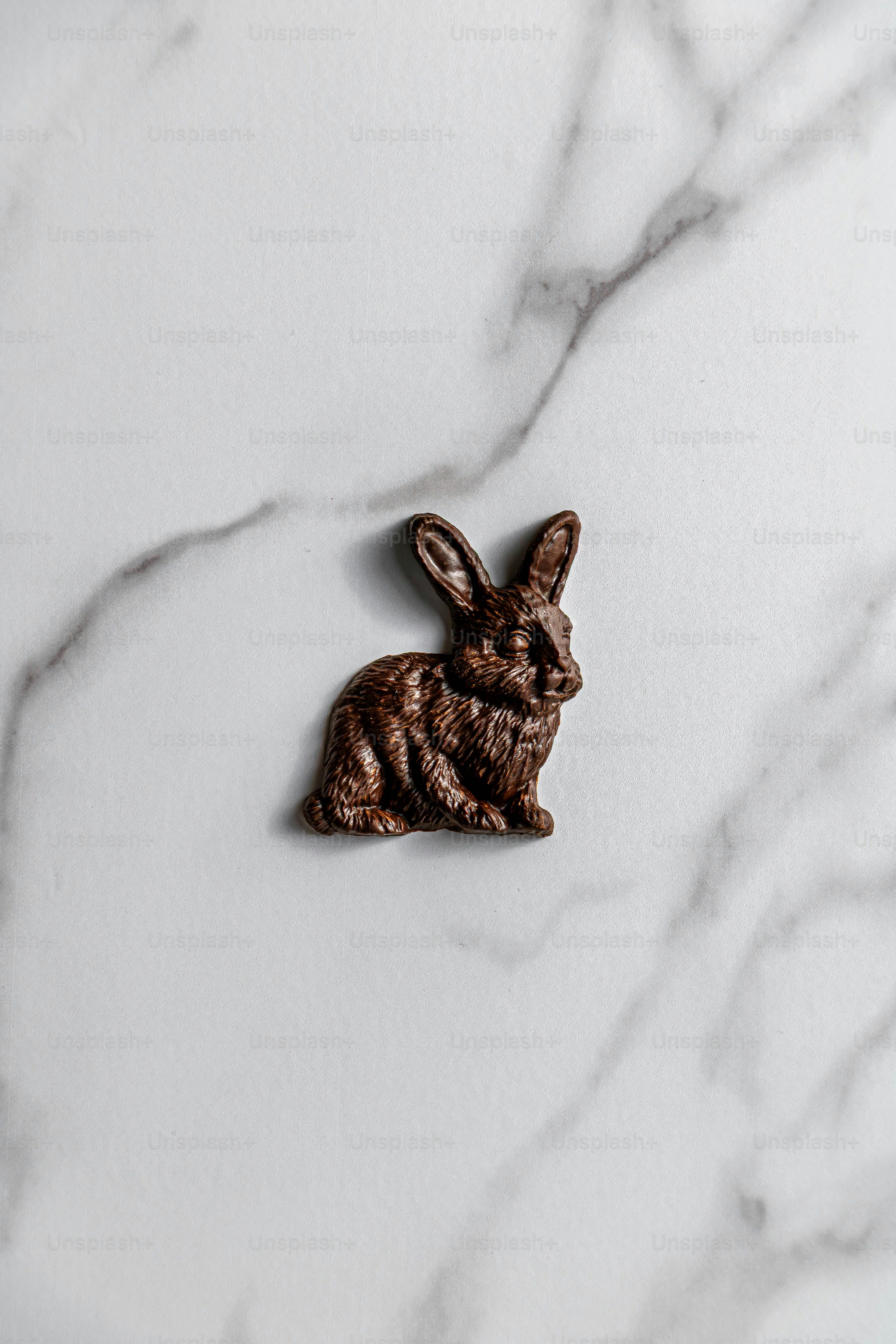 Un pequeño conejito de chocolate se posa sobre una superficie de mármol