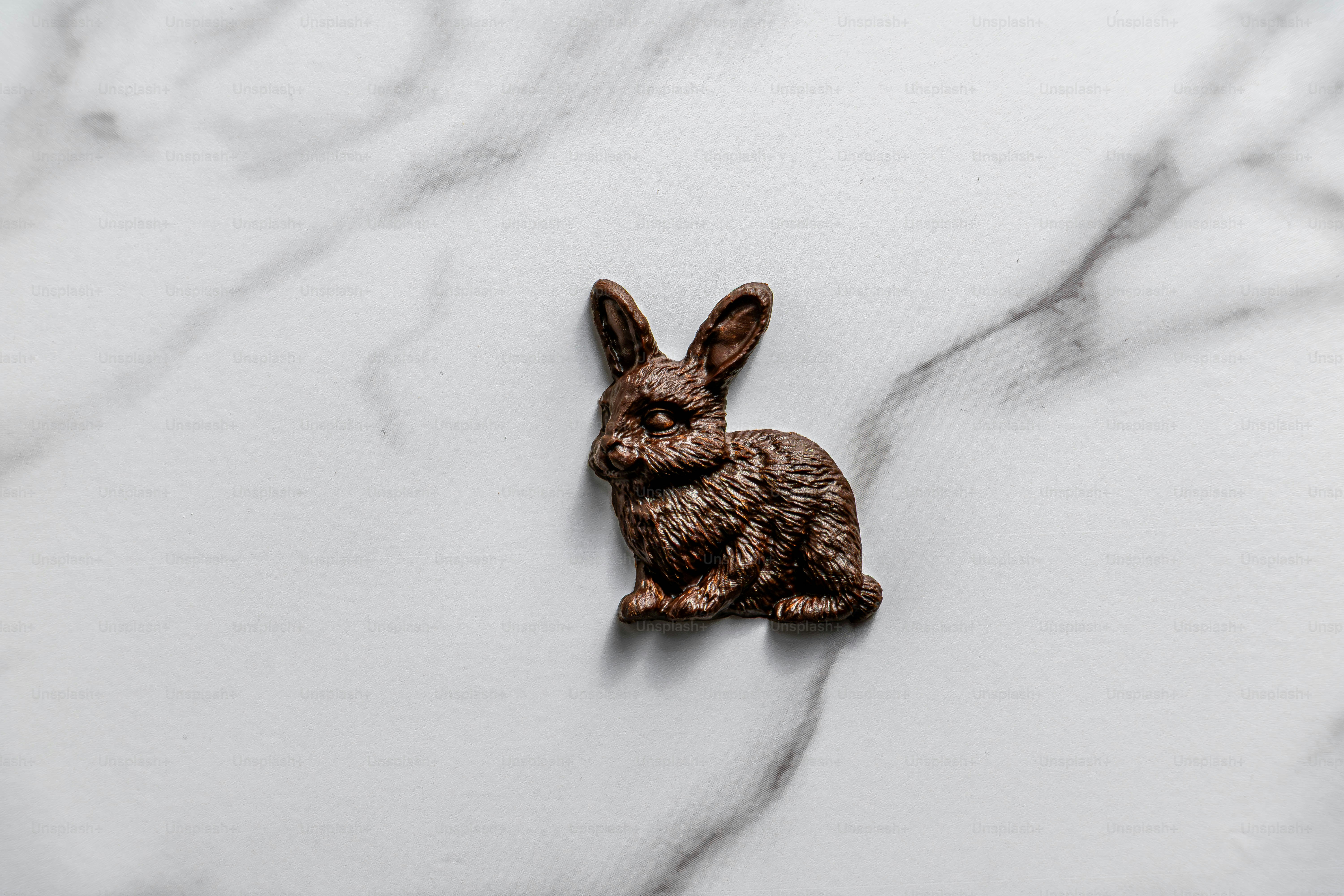 Un pequeño conejito de chocolate está sobre una superficie de mármol.