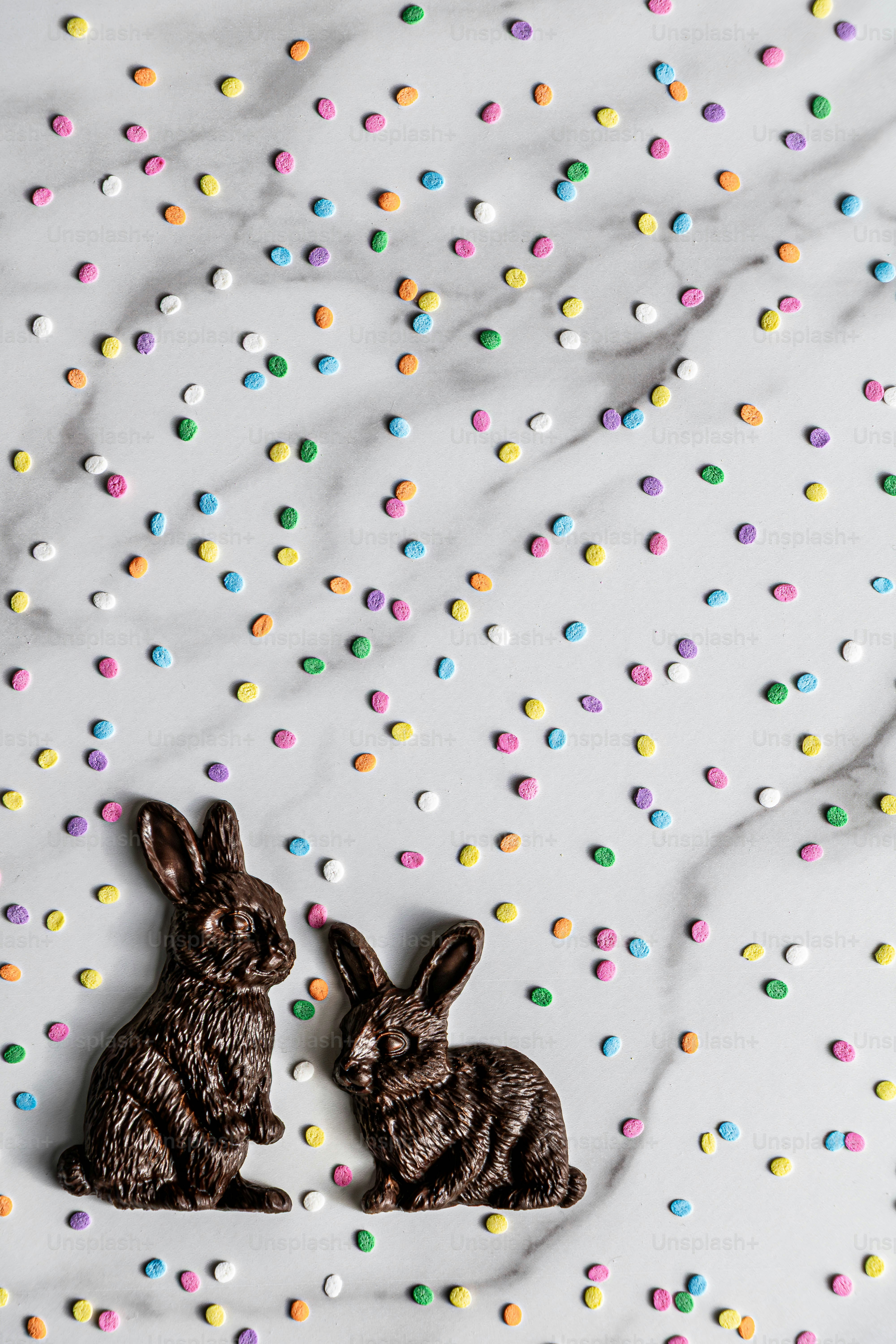 Dos conejitos de chocolate rodeados de coloridas chispas sobre mármol