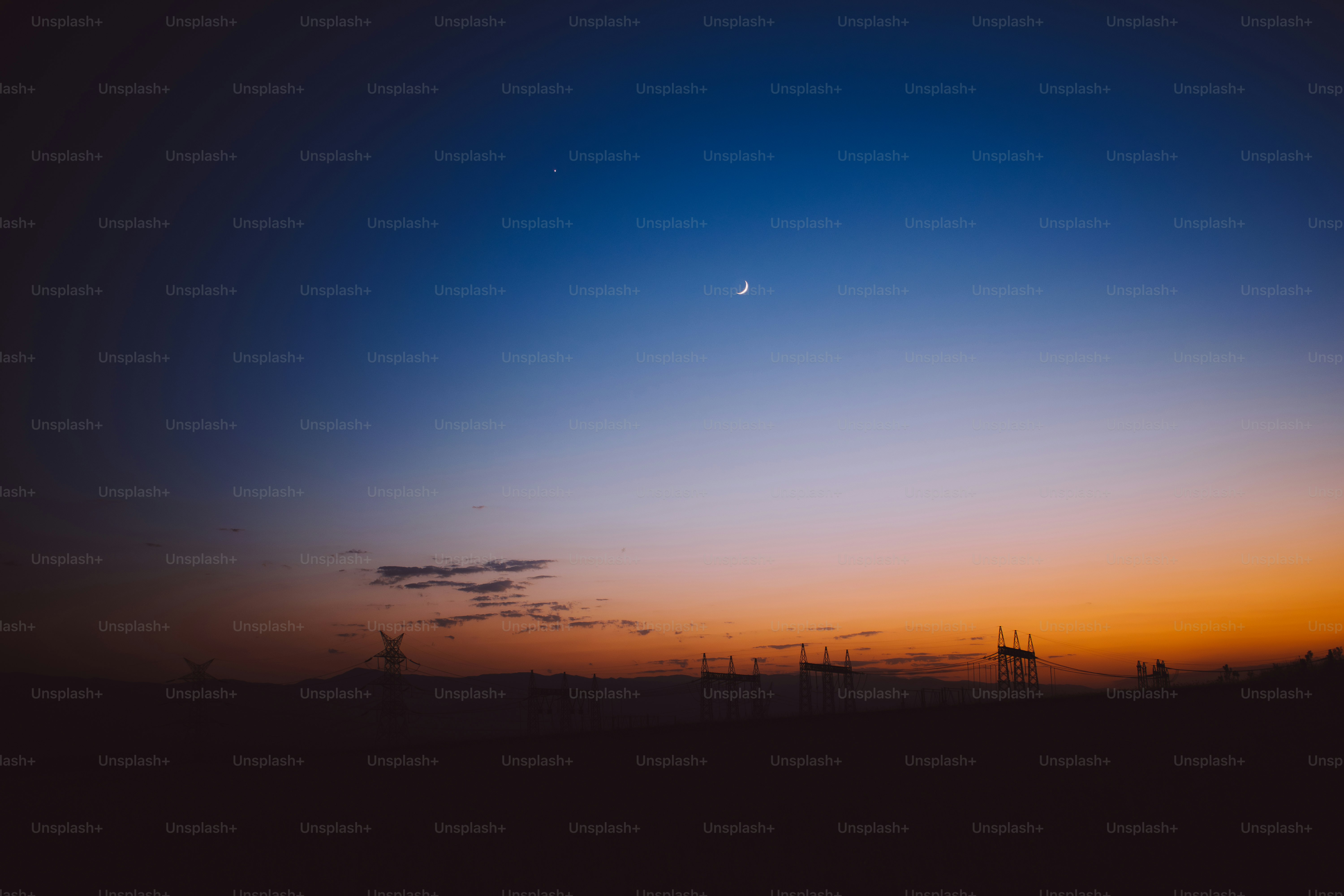 Dusk sky with faint moon and distant silhouettes