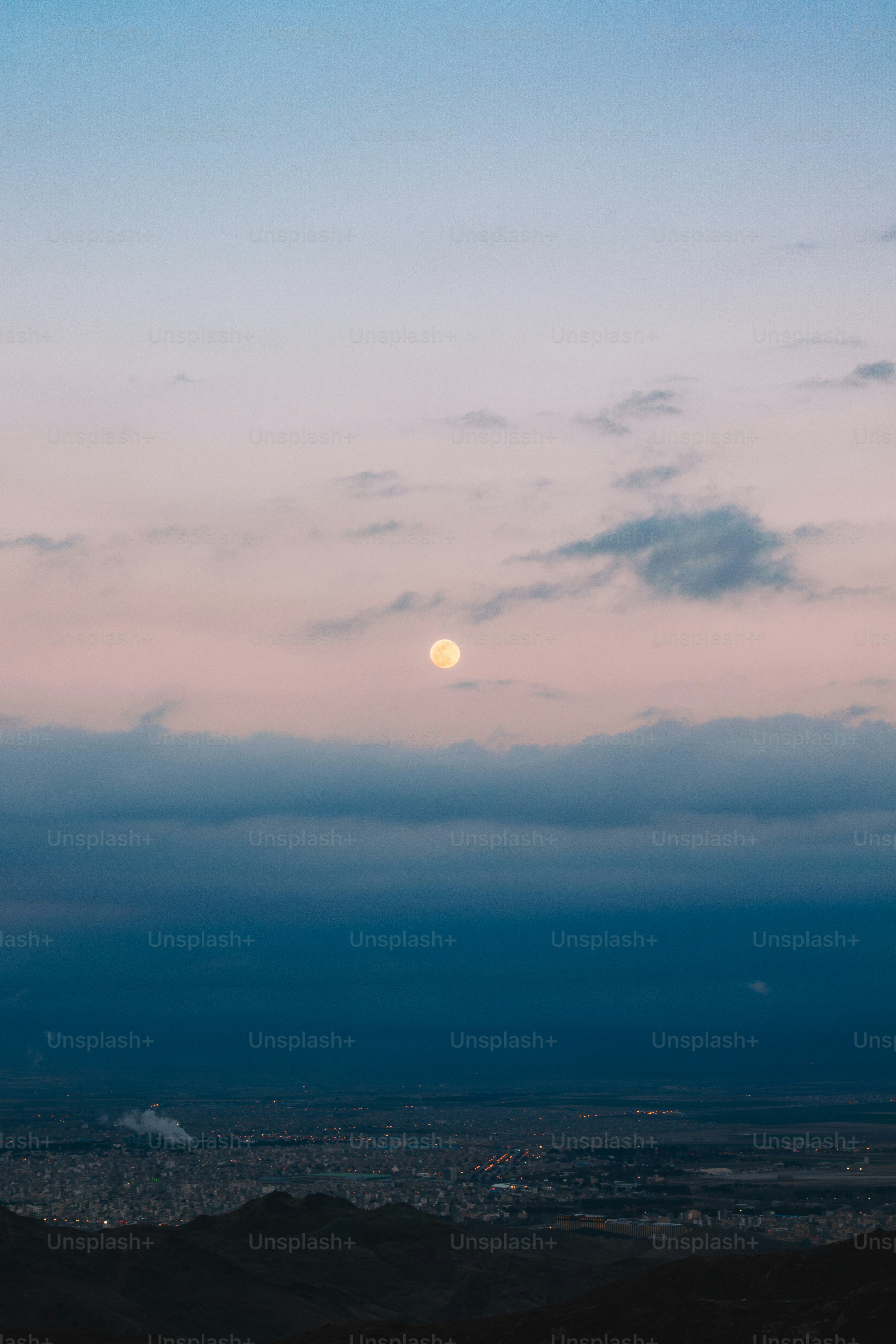 Full moon rises over a city at dusk