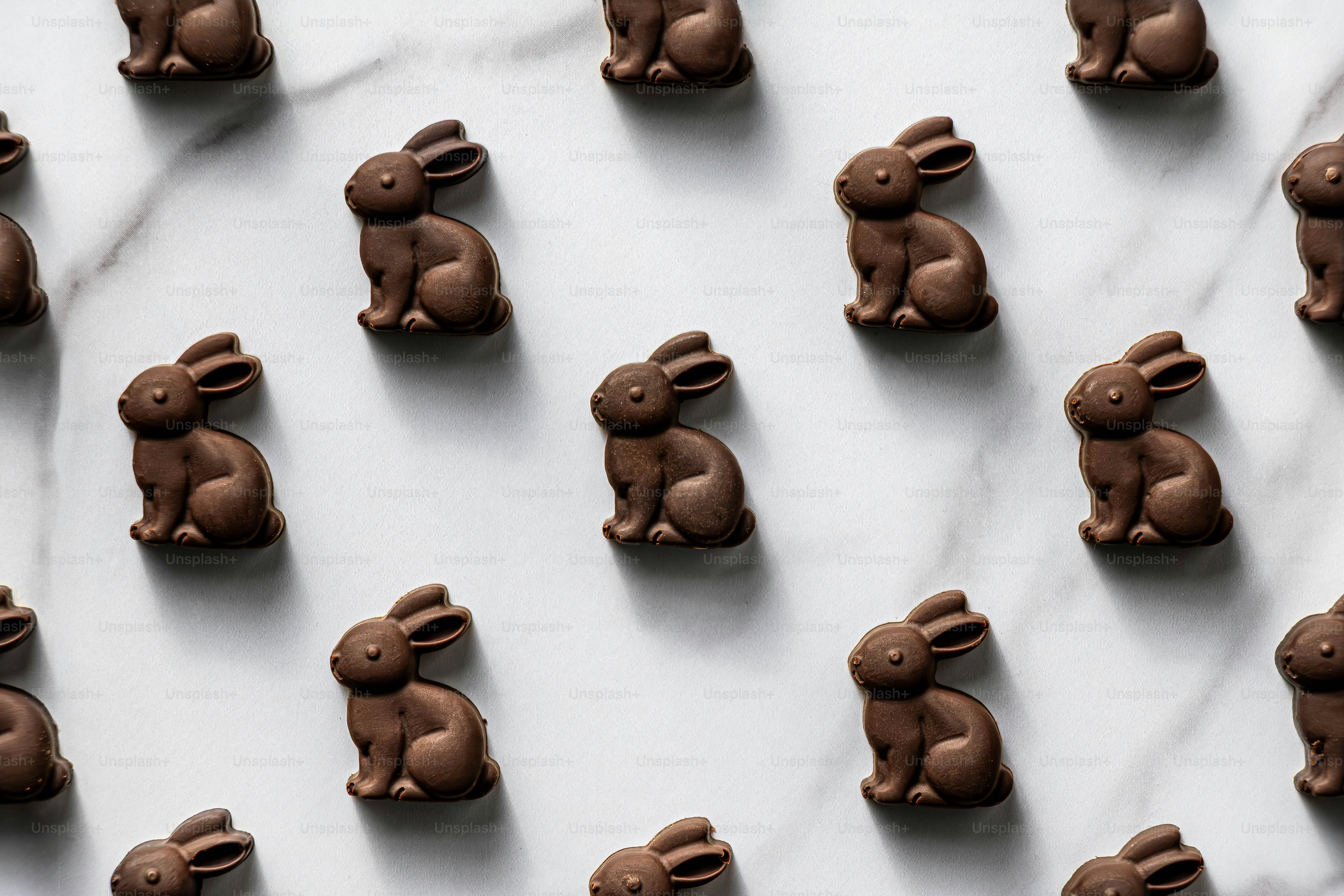 Filas de conejitos de chocolate de Pascua sobre una superficie de mármol.
