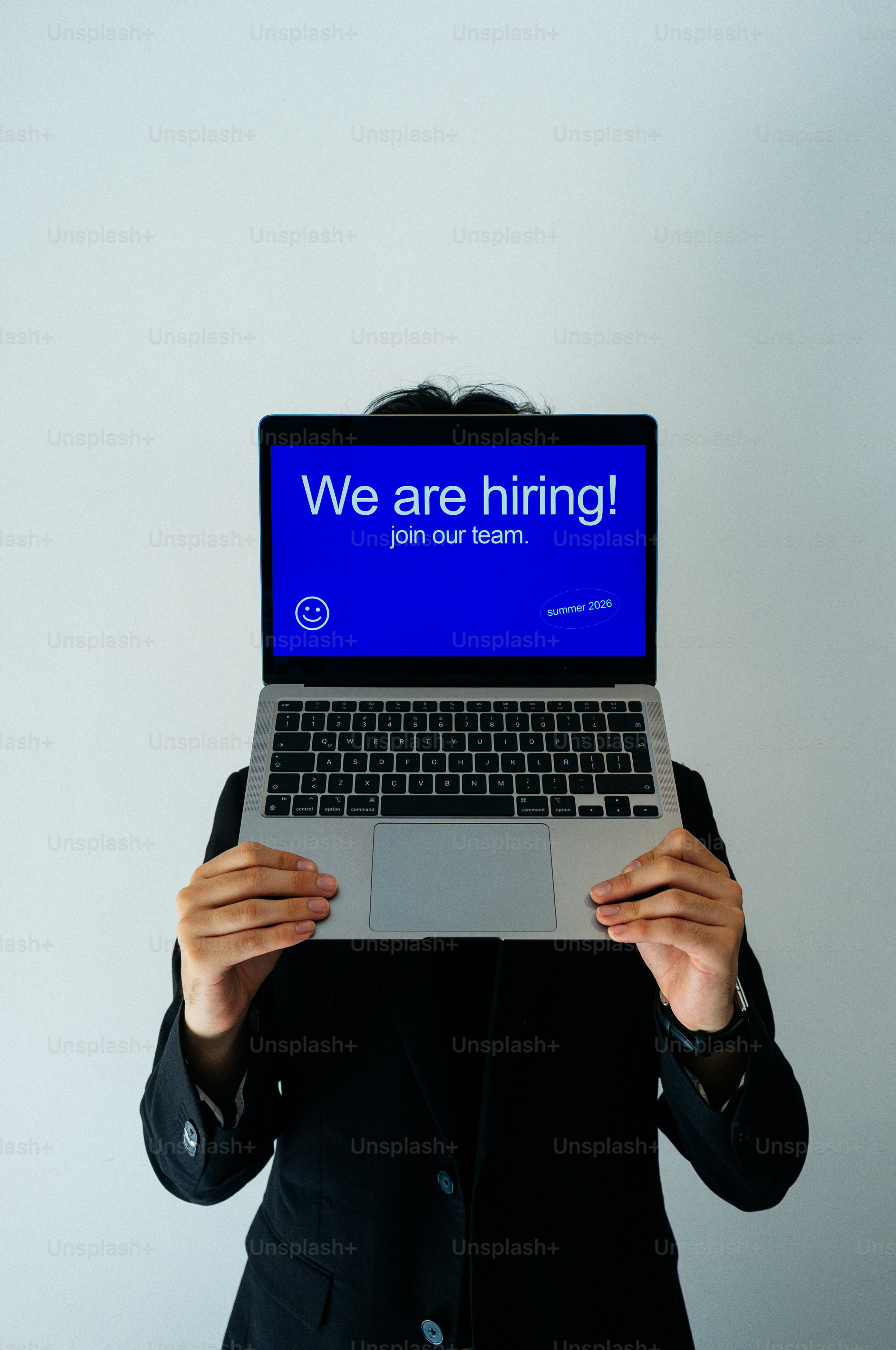 Person holds laptop showing "we are hiring!" message.