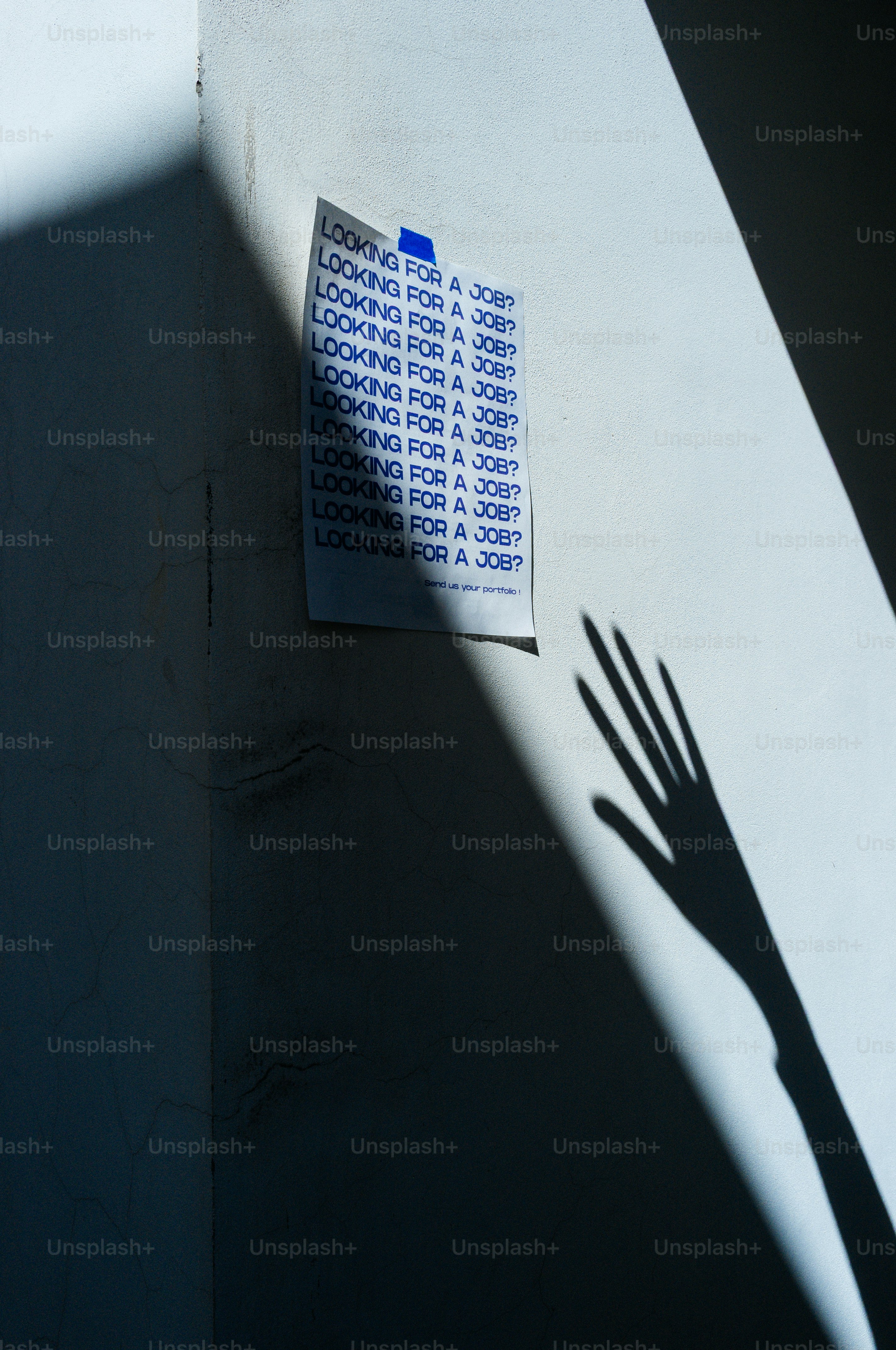 Hand Shadow tend la main vers un flyer de recherche d’emploi accroché au mur.