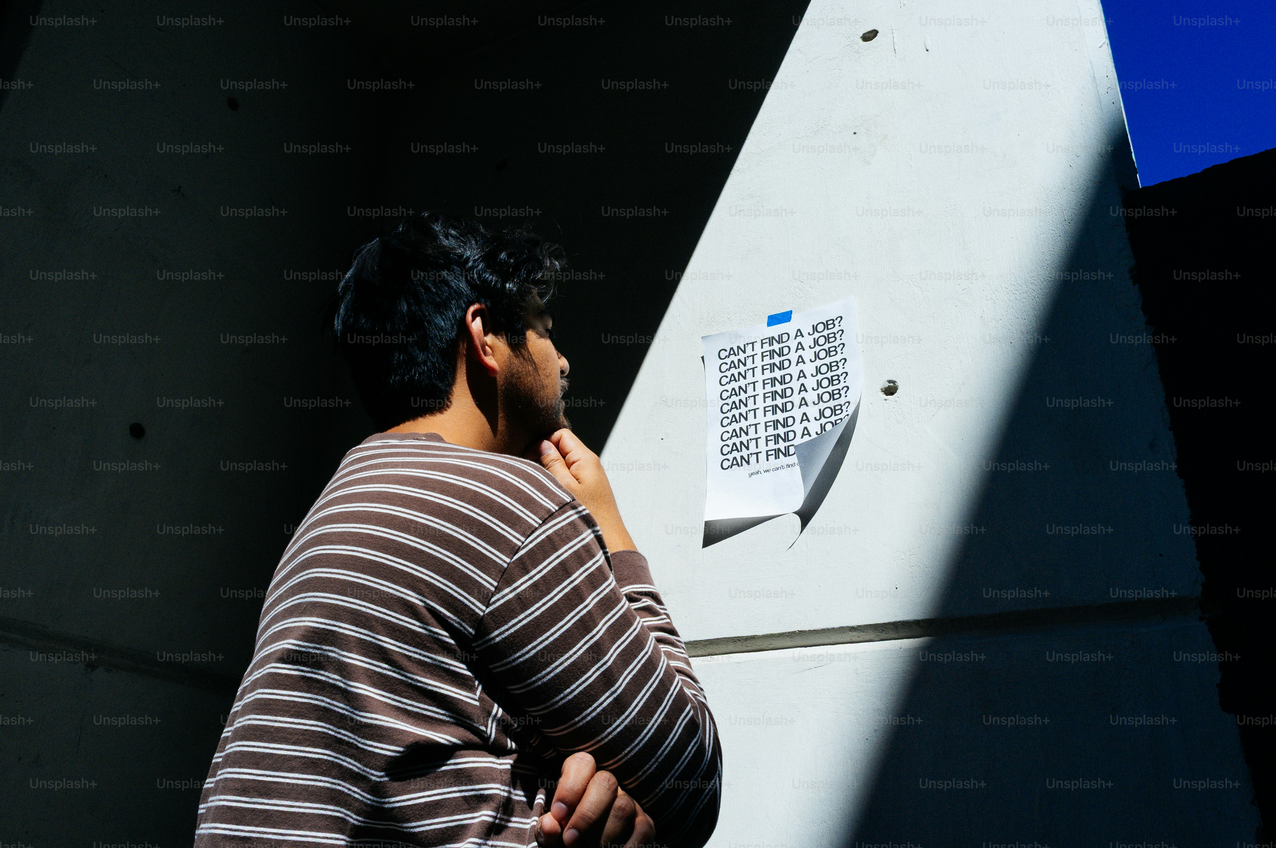 Jeune homme regardant un panneau accroché au mur.