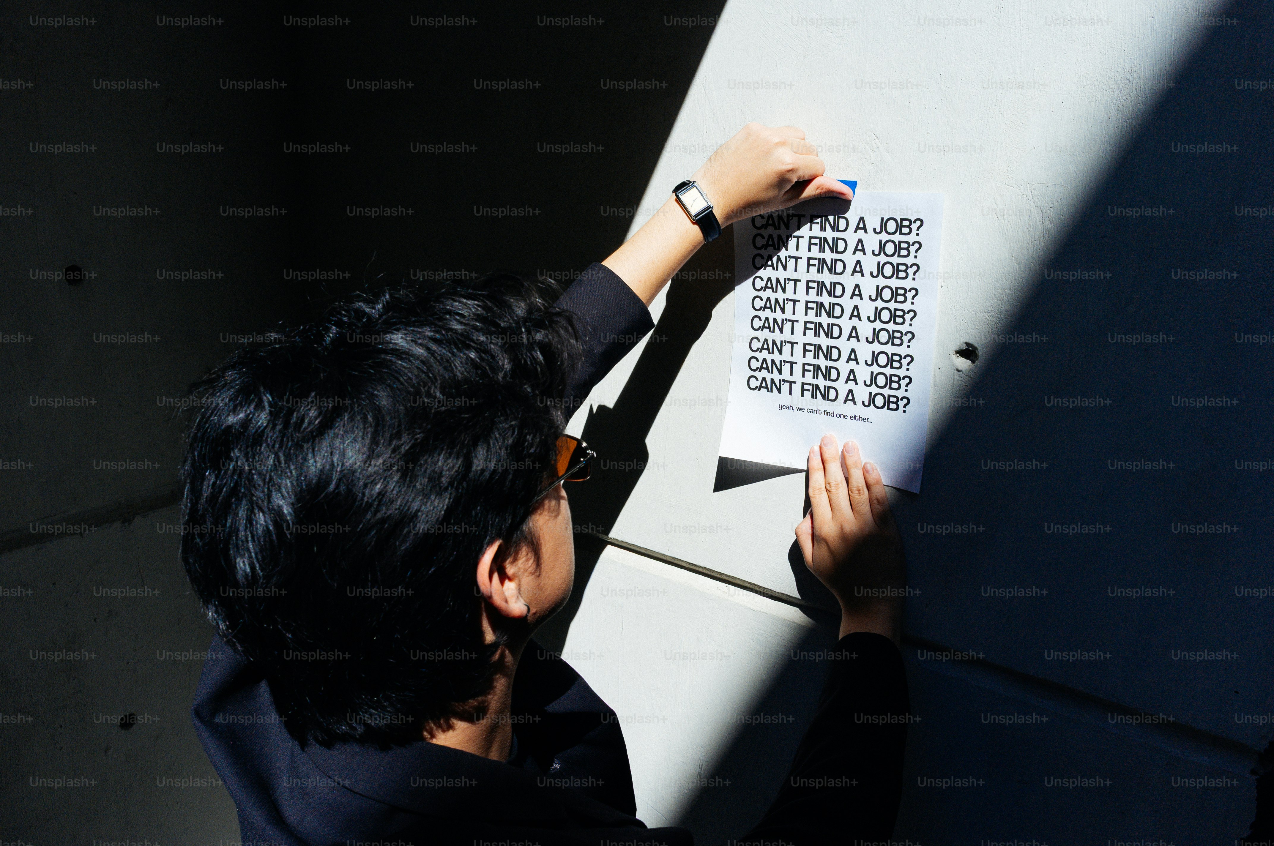 Une personne accroche une affiche qui dit « je ne trouve pas de travail »