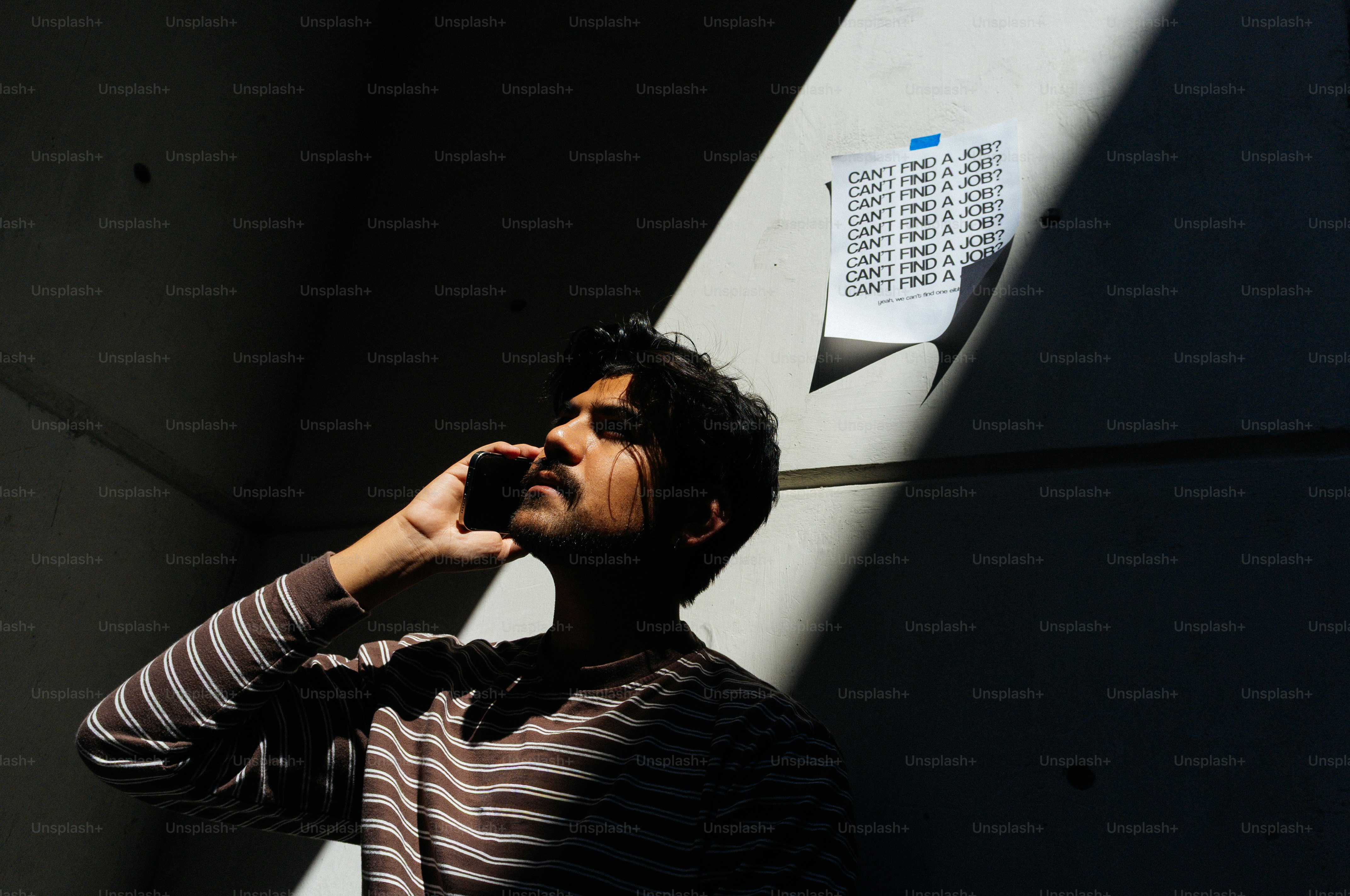 Homme en chemise rayée parlant au téléphone dans l’ombre