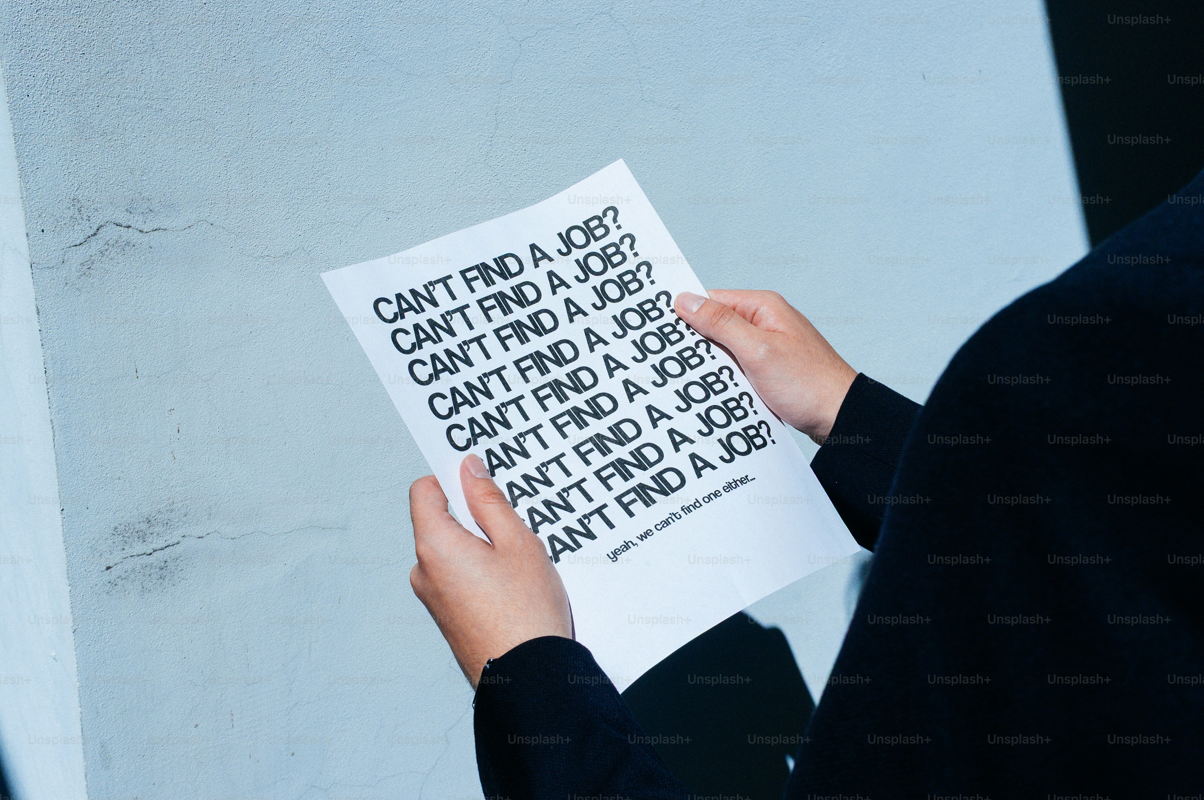 Une personne tenant un papier avec « ne trouve pas de travail ? » répétait.