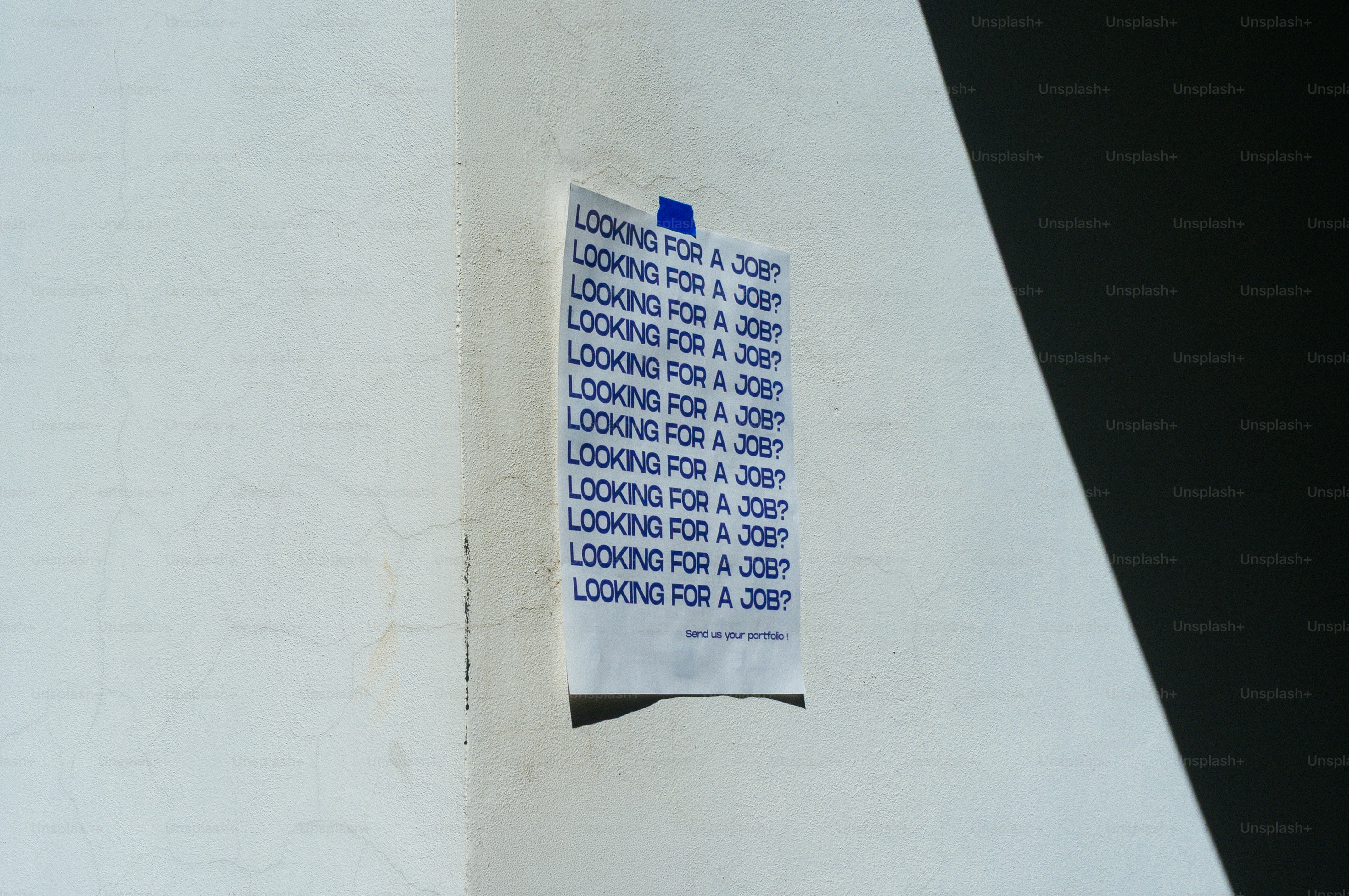 Une affiche accrochée au mur dit « cherche un emploi » à plusieurs reprises.