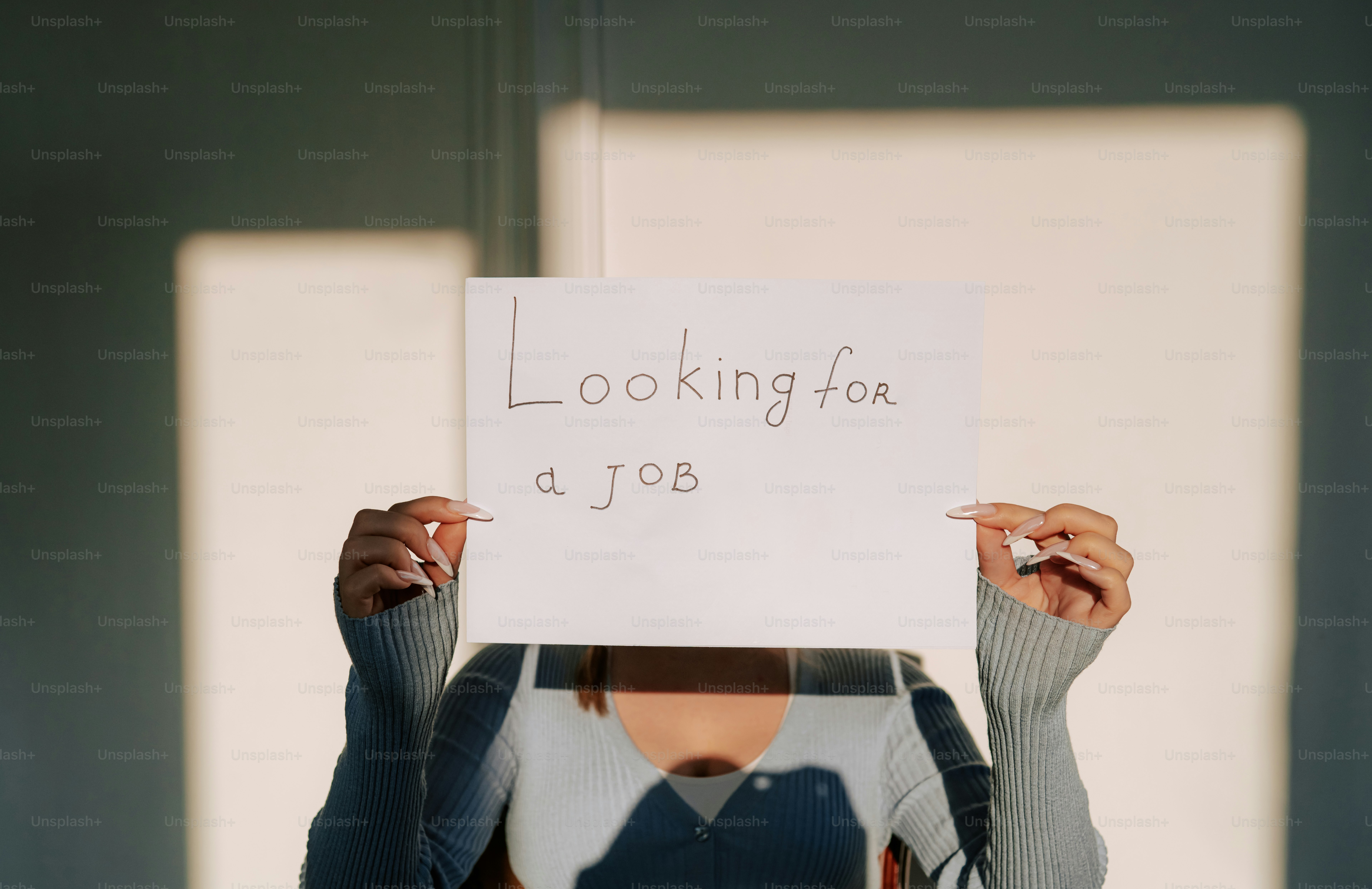 Persona que sostiene un cartel que dice "buscando trabajo"