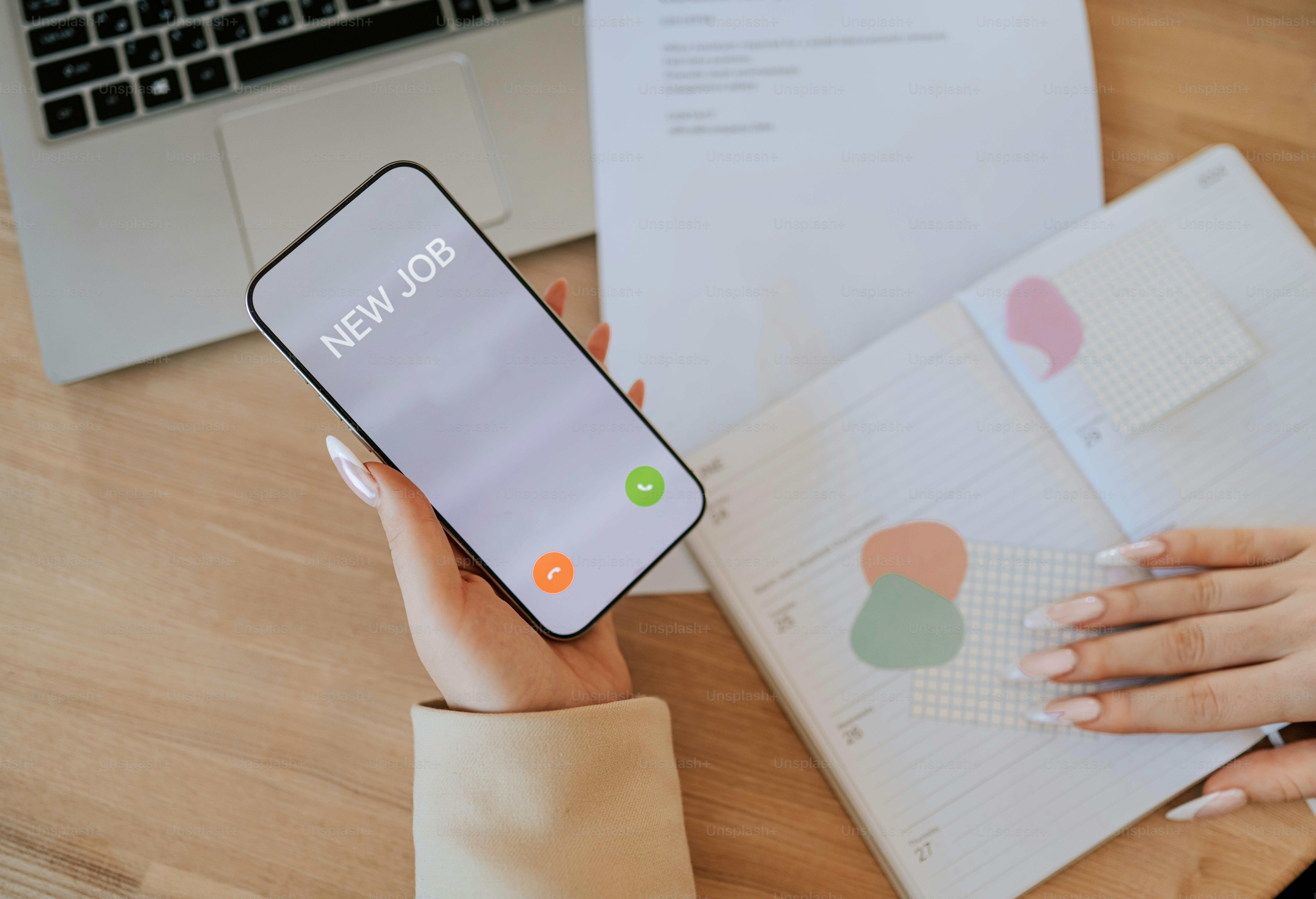 Smartphone exibe tela de chamada de "novo emprego" sobre a mesa com caderno