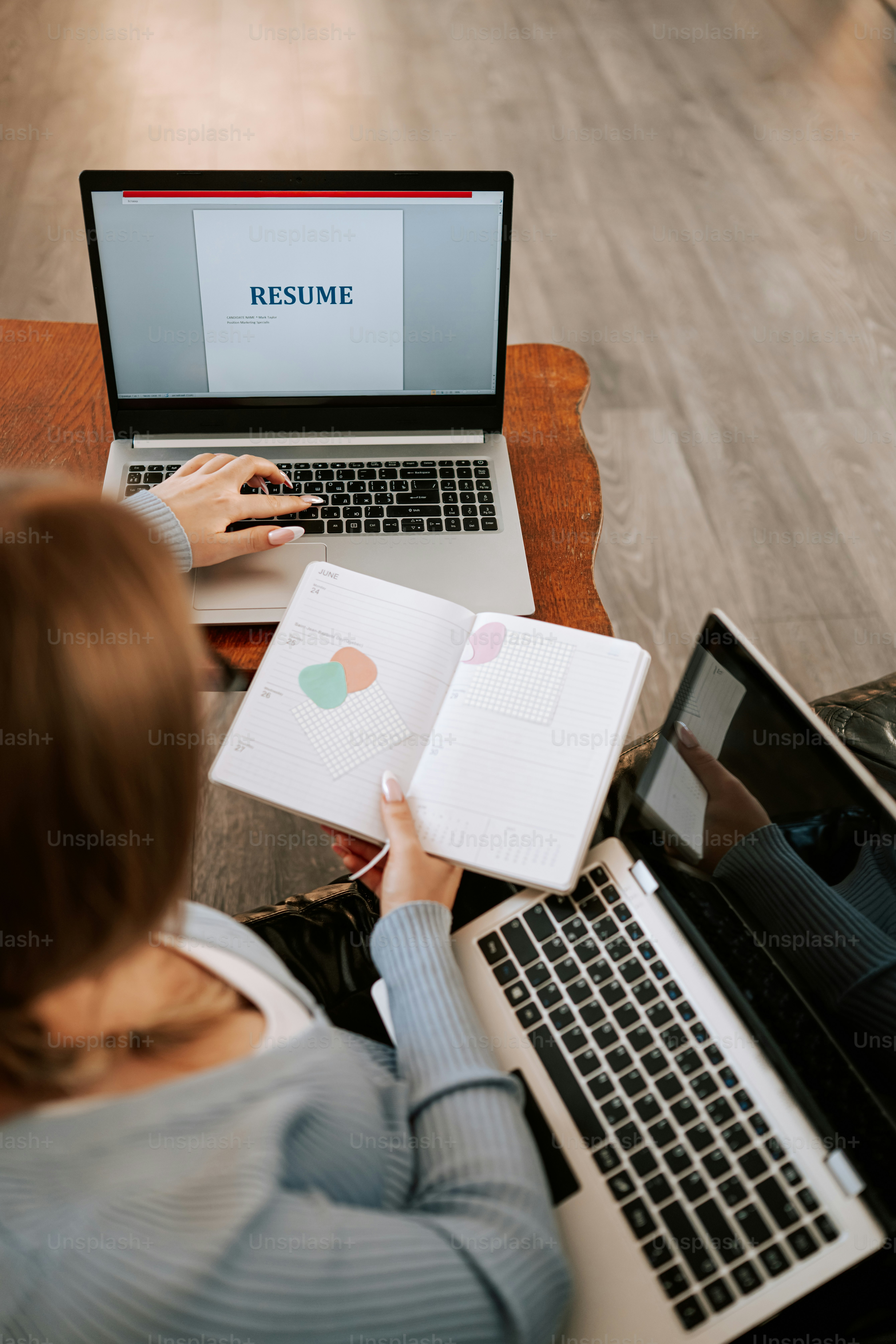 Wanita mengetik di laptop dengan resume di layar.