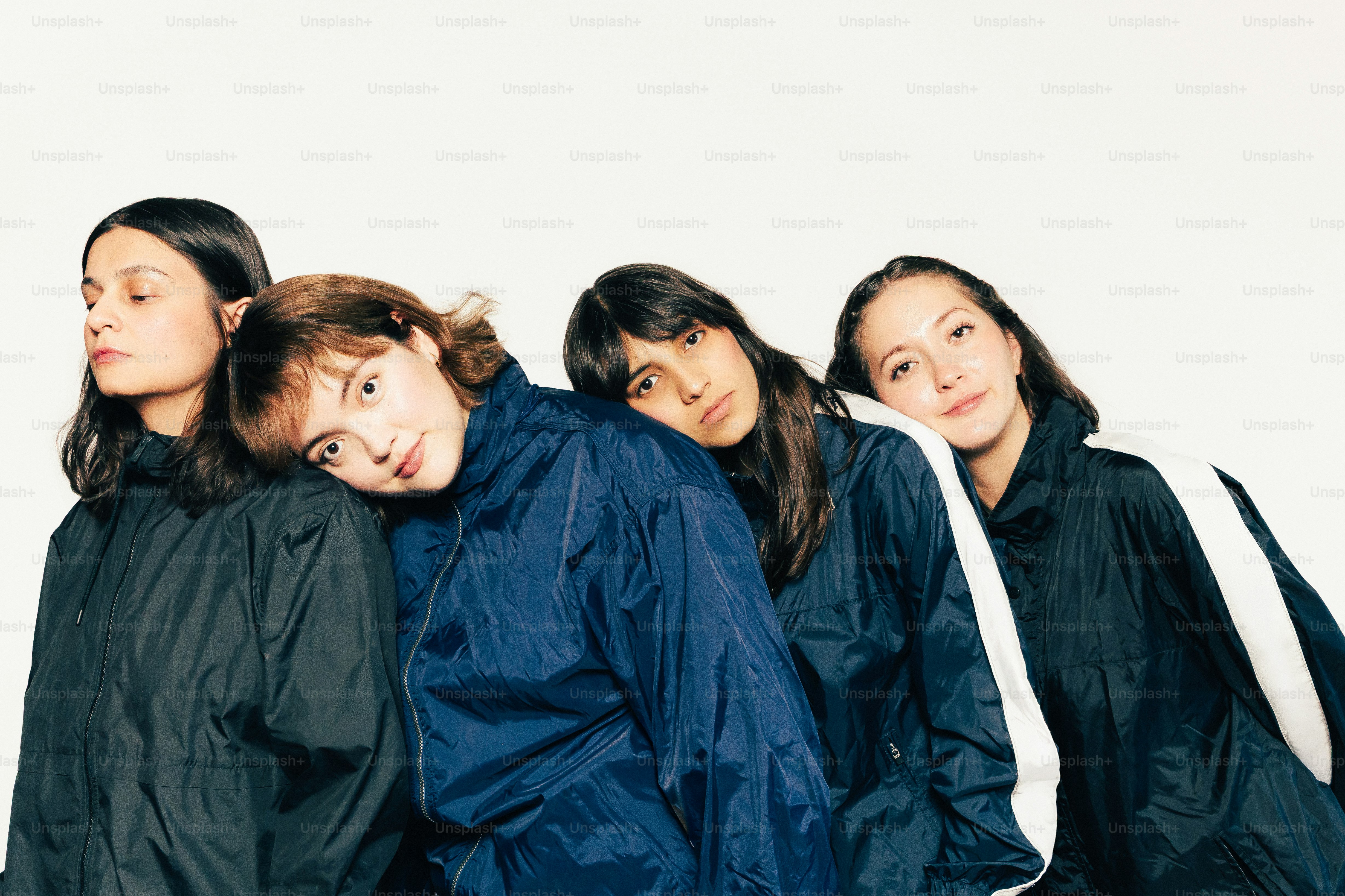 暗いジャケットを着た4人の若い女性が寄り添っている