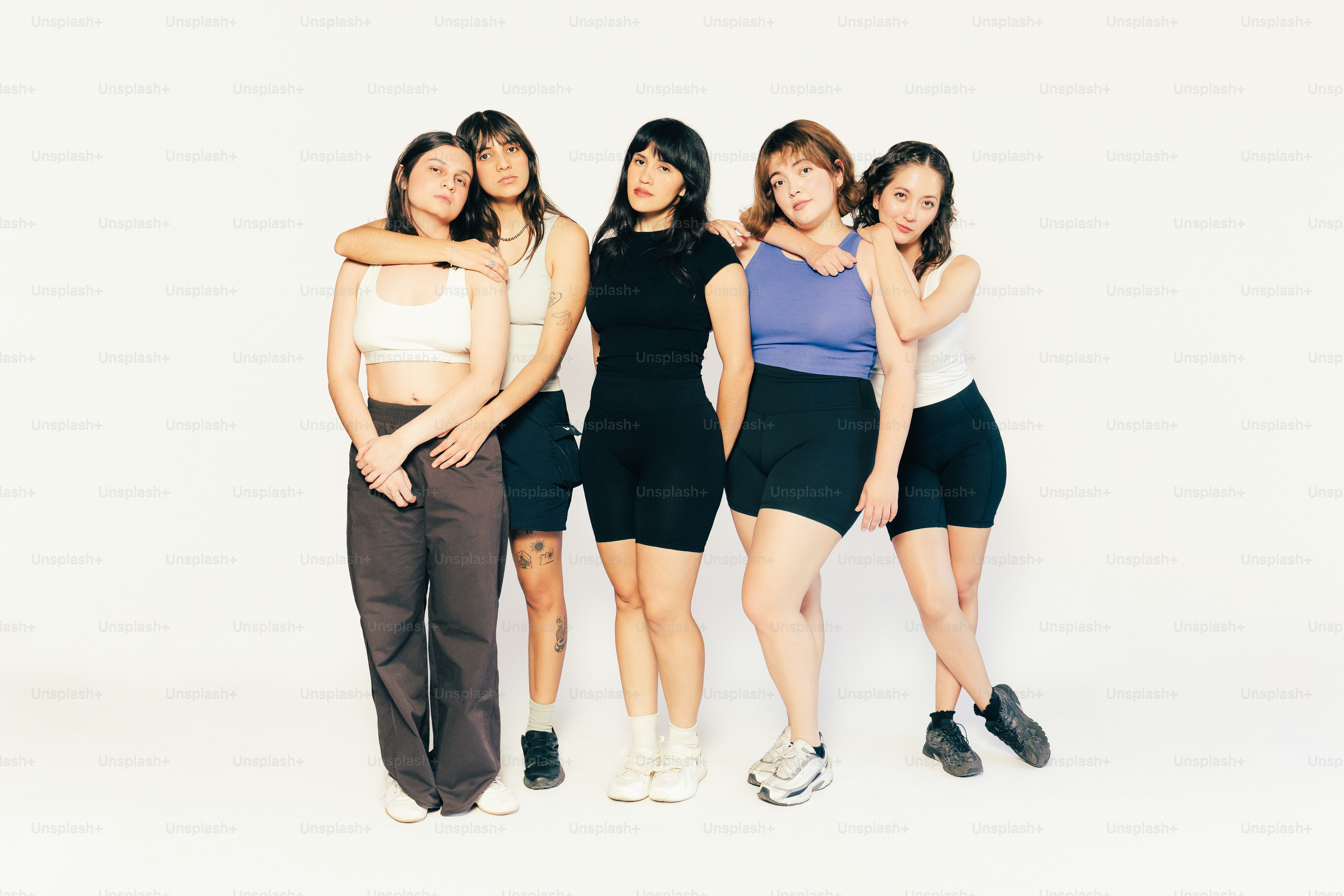 5人の若い女性が白い背景を背景に並んで立っています。