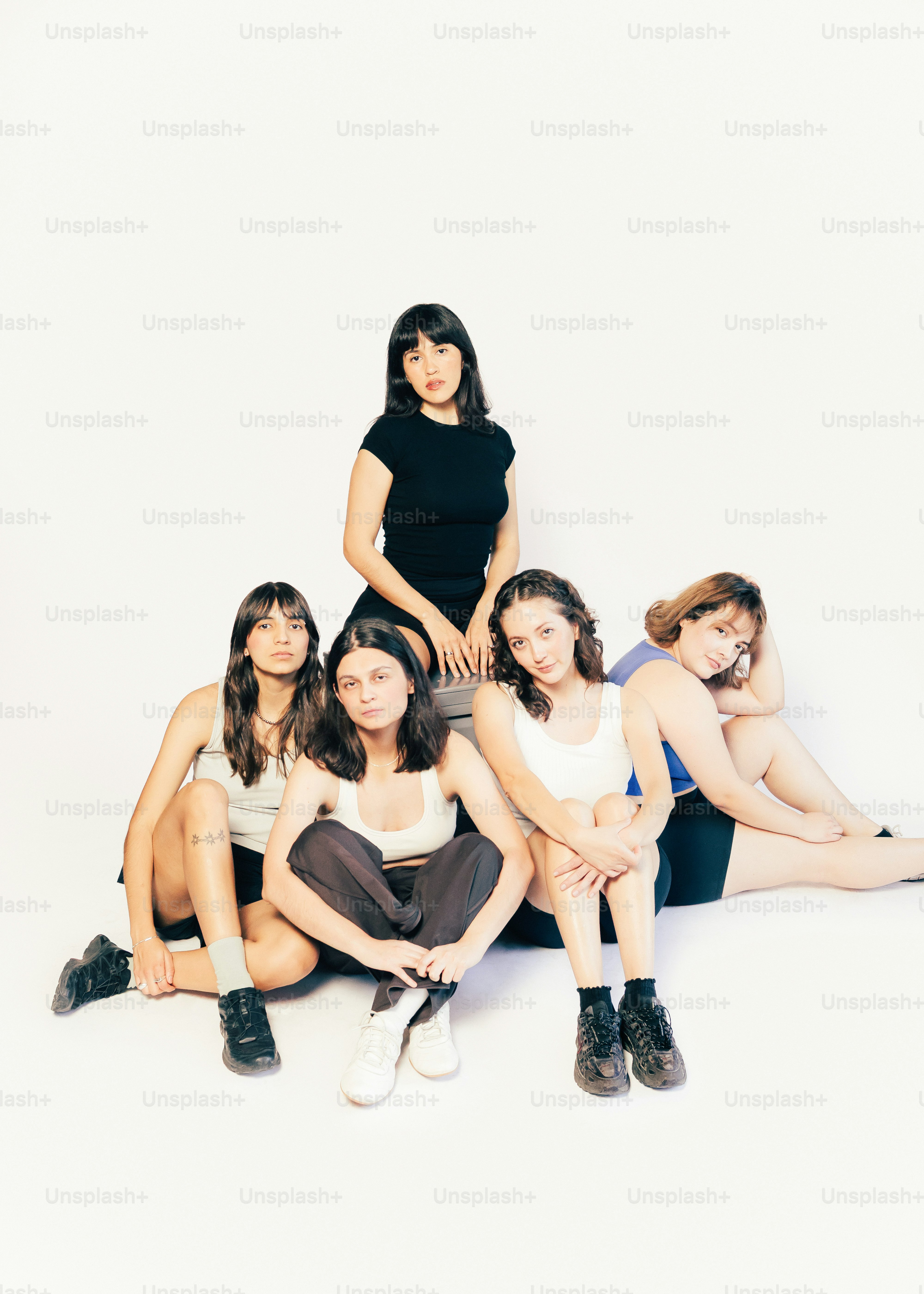 白い背景で一緒にポーズをとる5人の若い女性たち