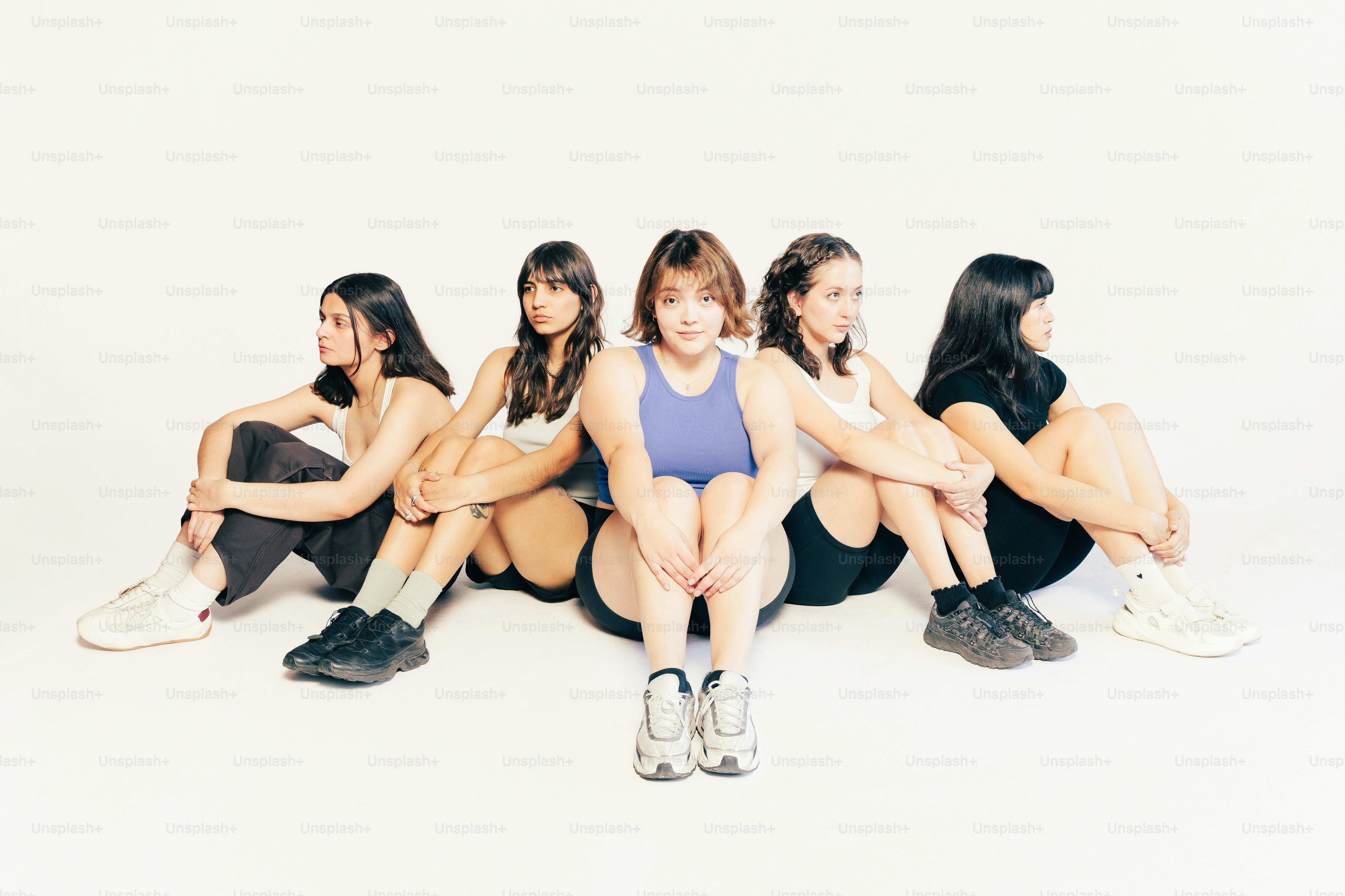 五人の若い女性が外向きに円になって座っている。