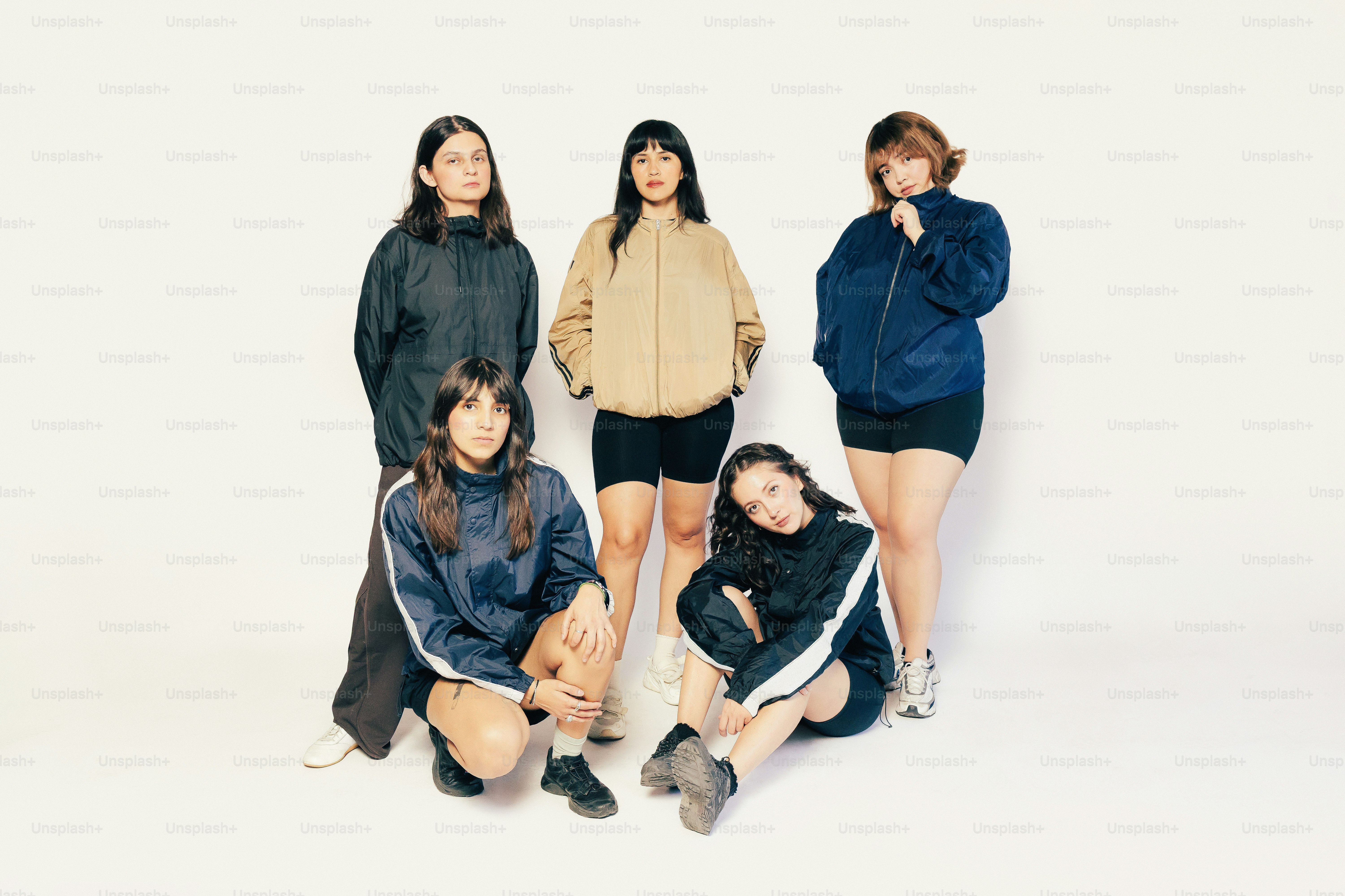 白い背景にアスレチックウェアを着た5人の若い女性がポーズをとっている
