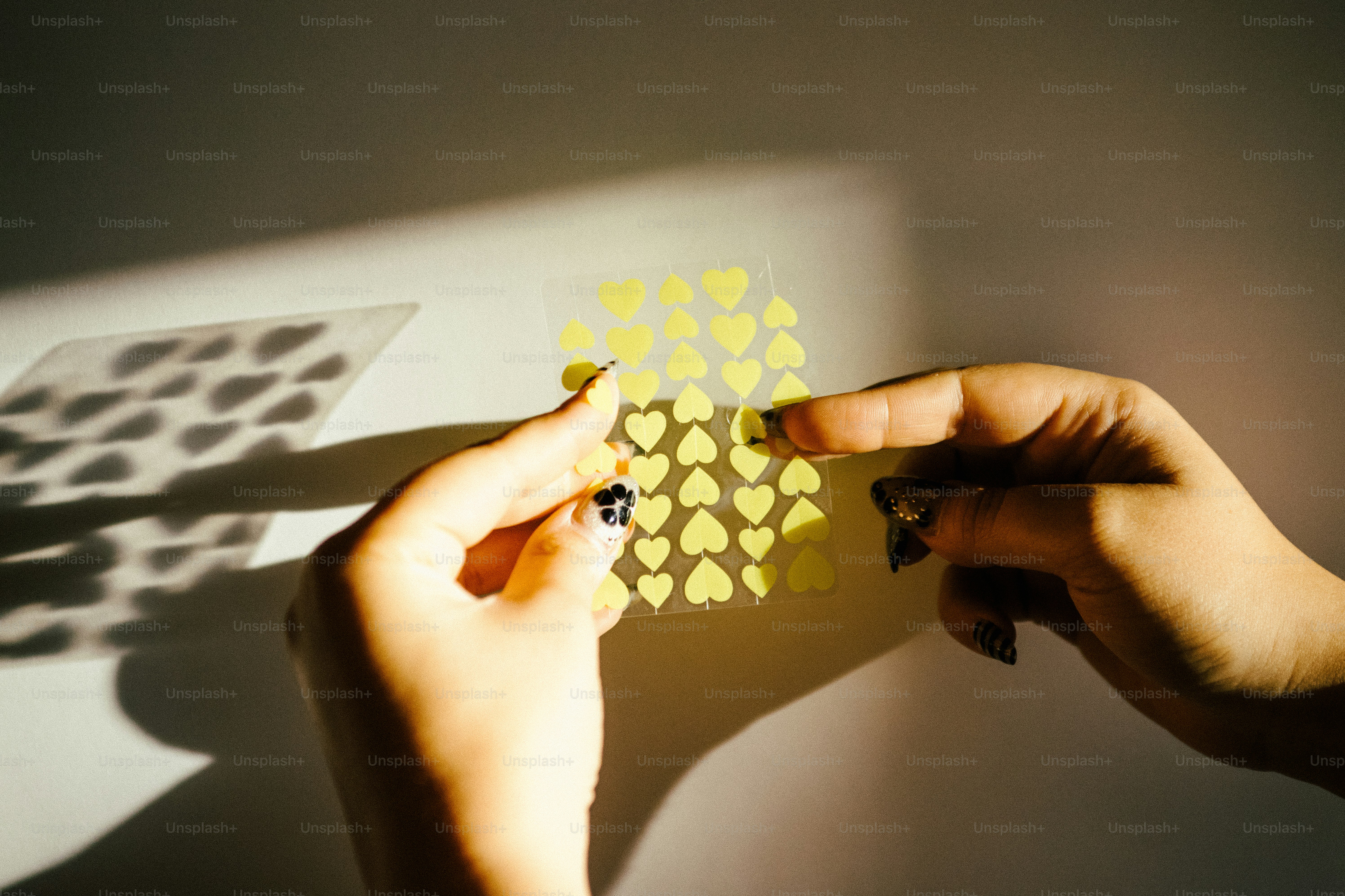 Hands holding sheet of yellow heart stickers
