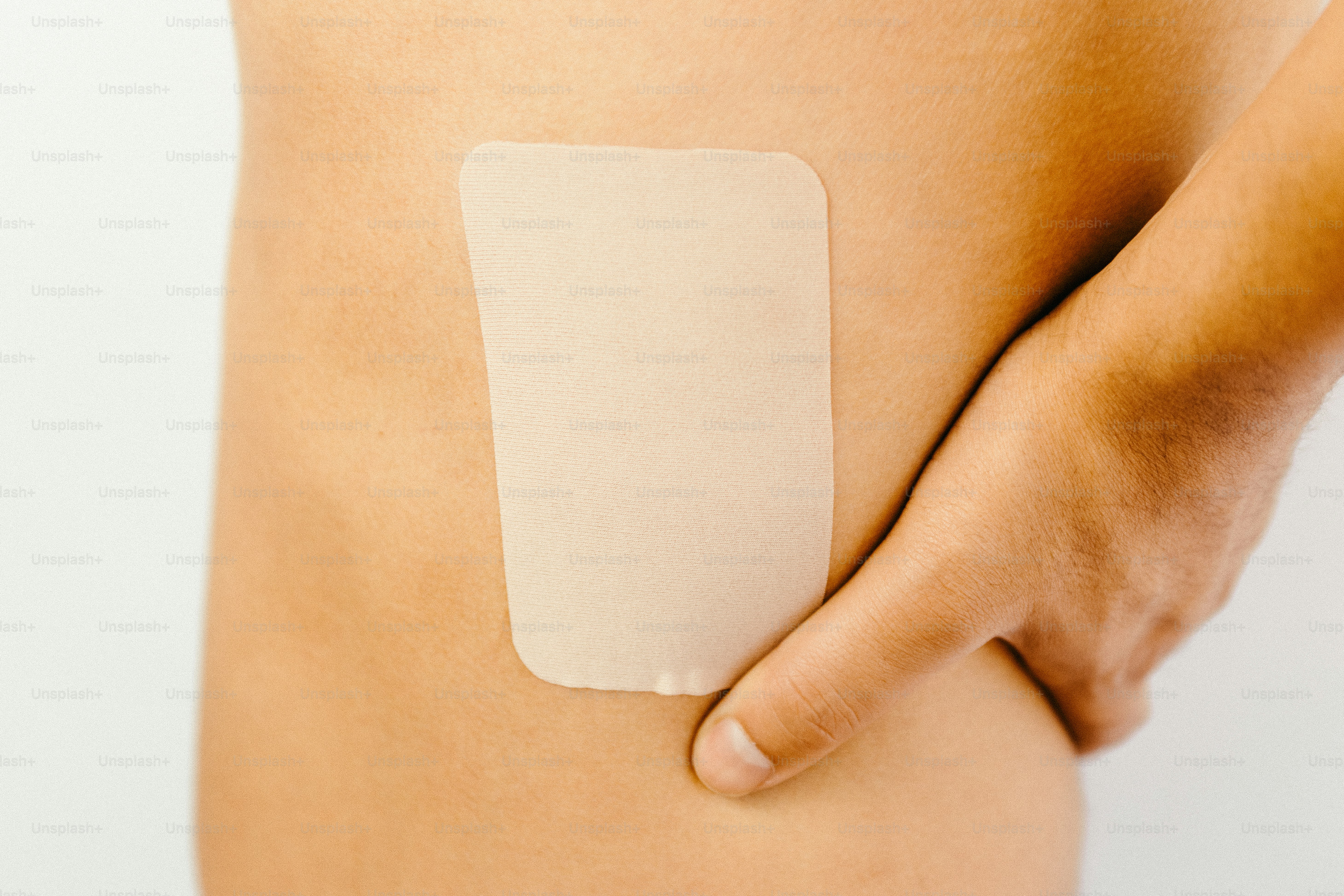 Person applying a clear patch to lower back. photo – Wellness Image on ...