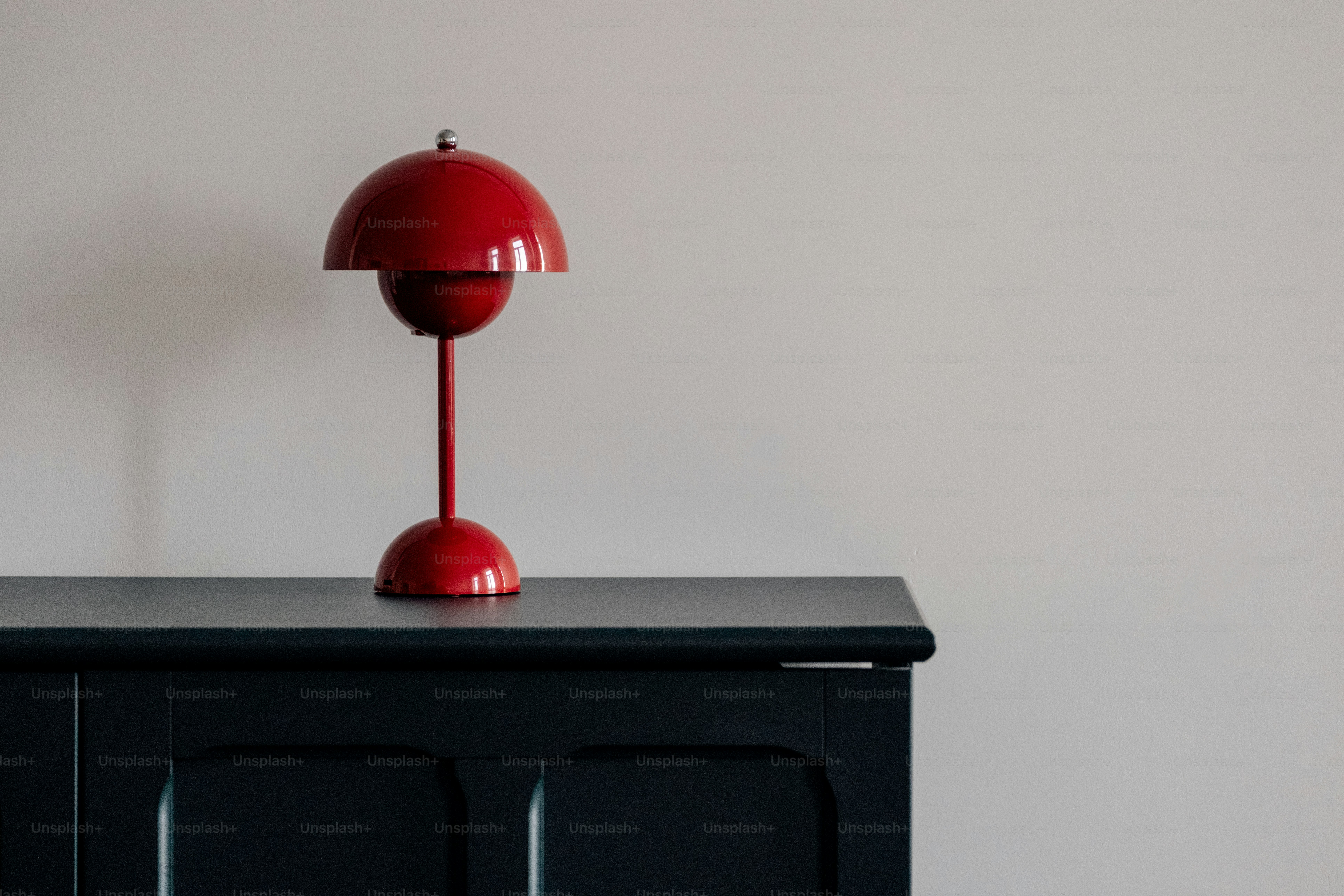 A red lamp sits on a dark cabinet