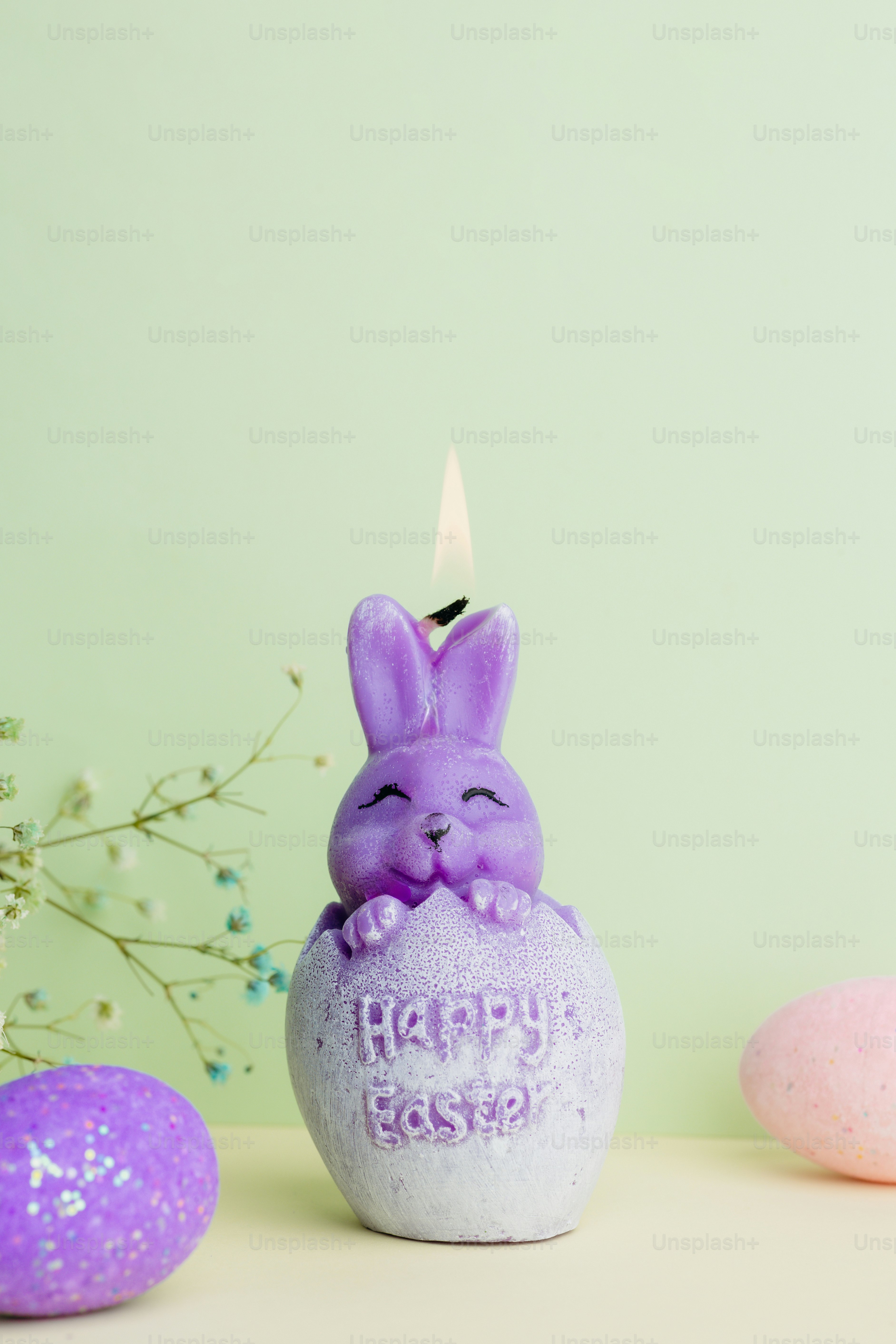 Vela de conejo morada con "feliz Pascua" en el huevo