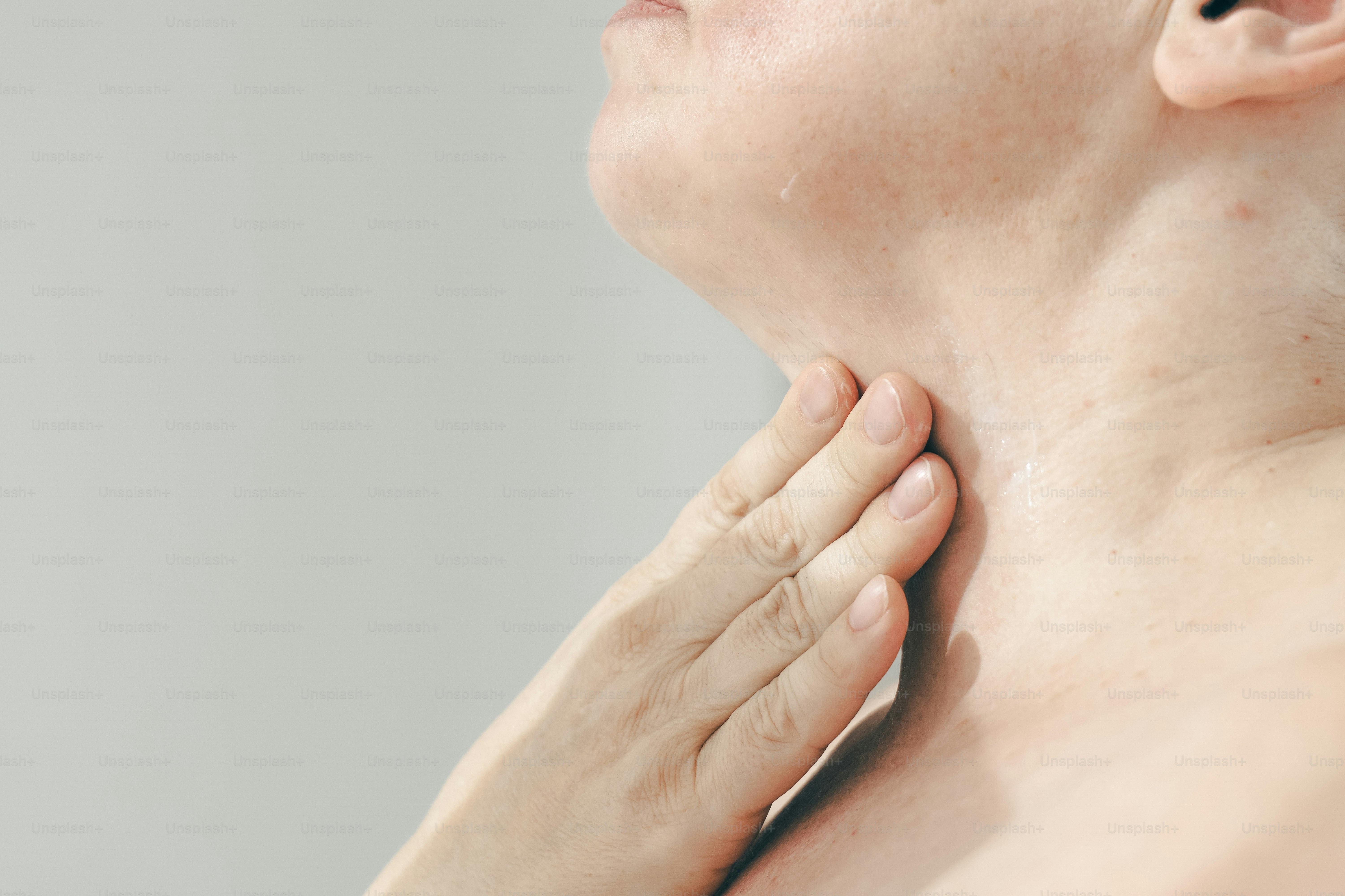 A hand gently touching a person's neck and throat.