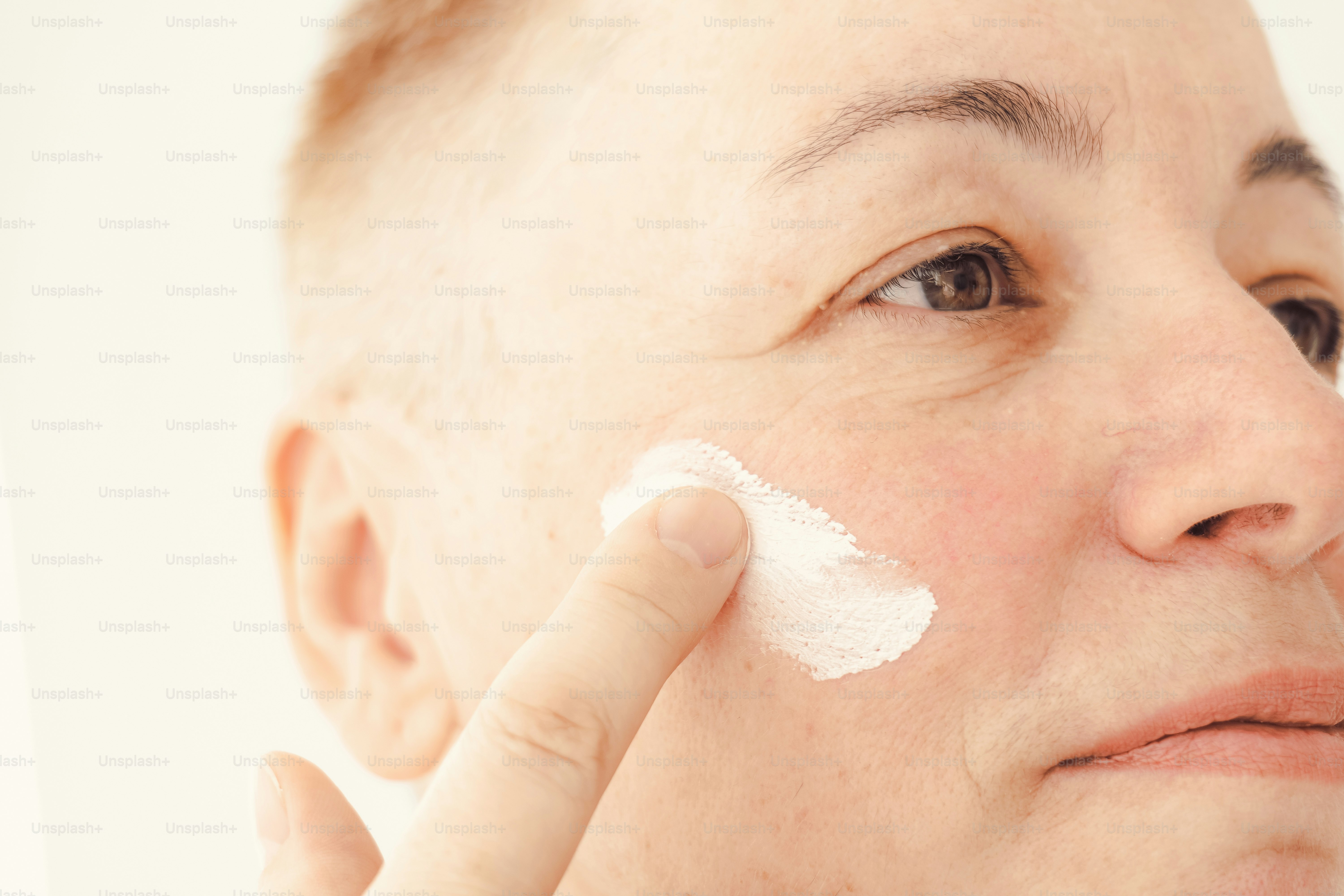 Woman applying cream to her cheek