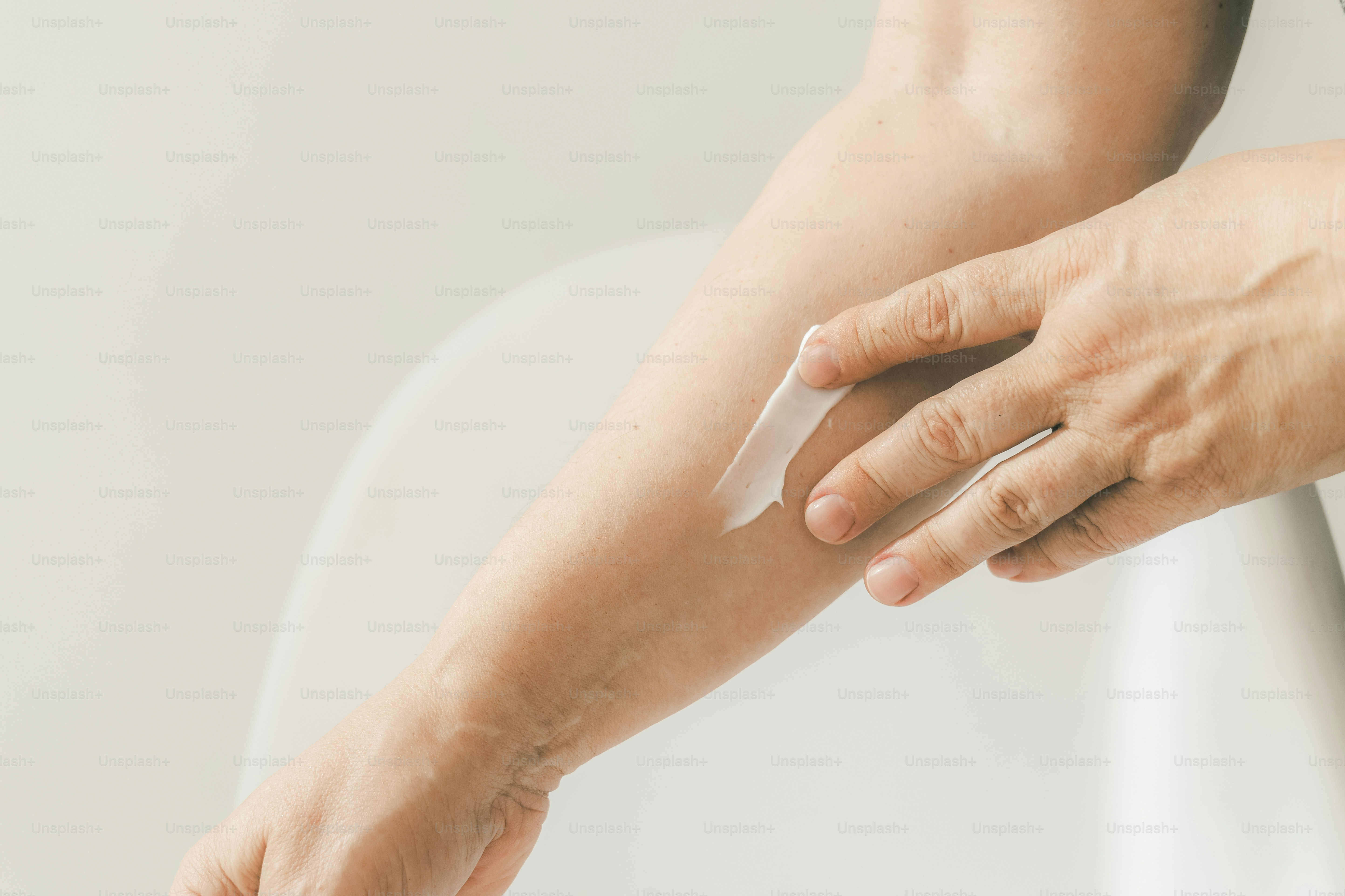 A hand applies lotion to an arm