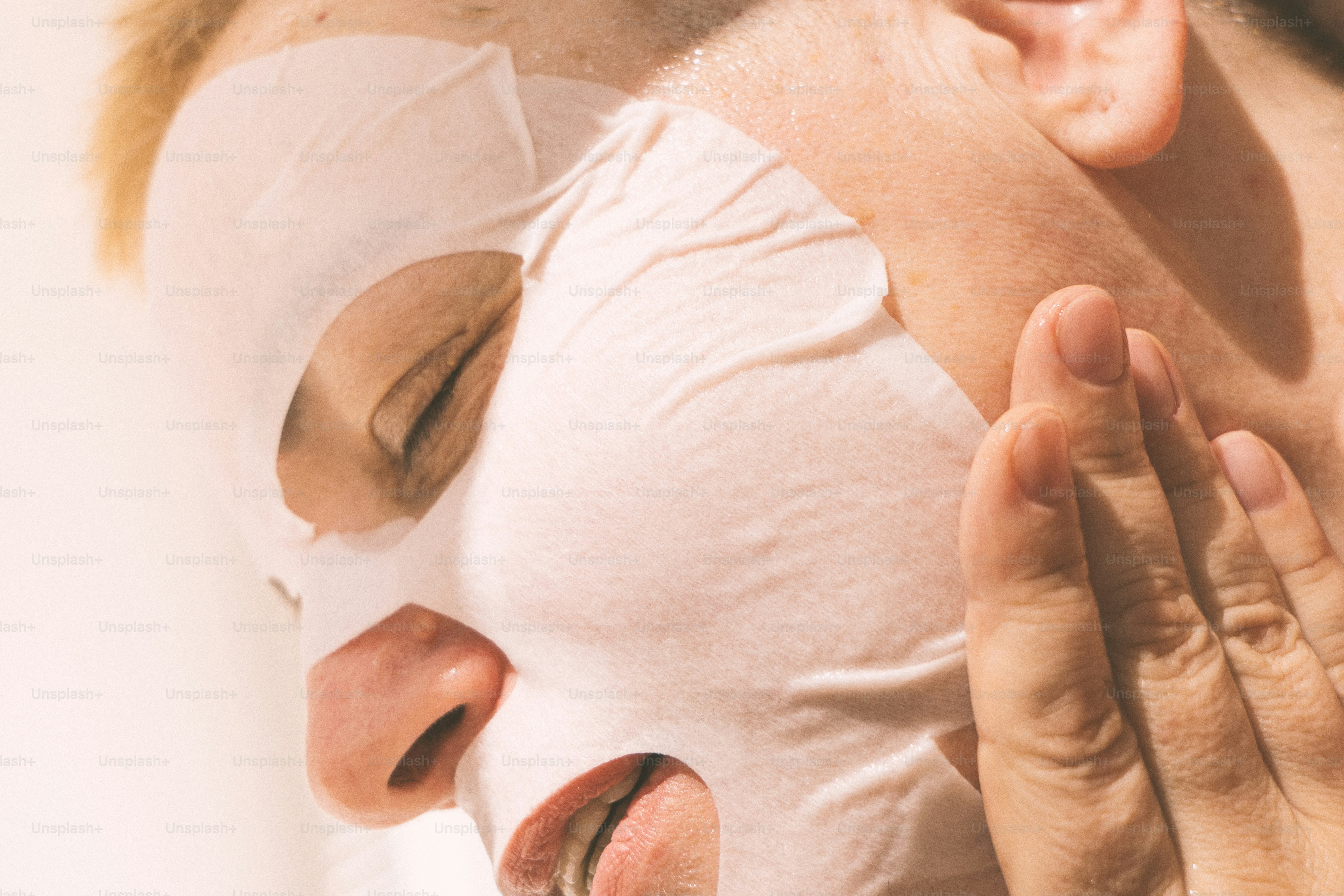 Woman applying a white sheet mask to her face