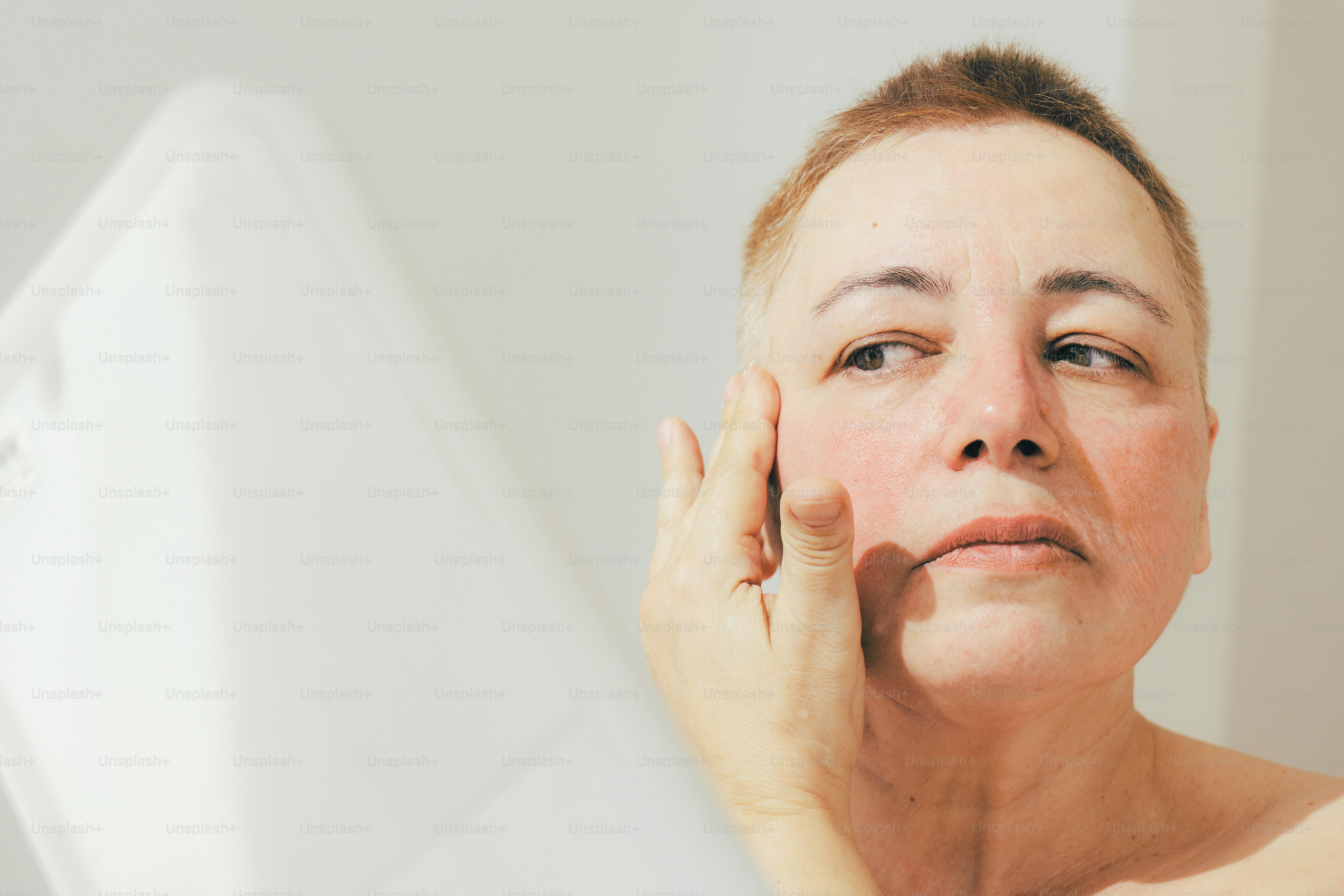 Woman touches her face in front of a mirror