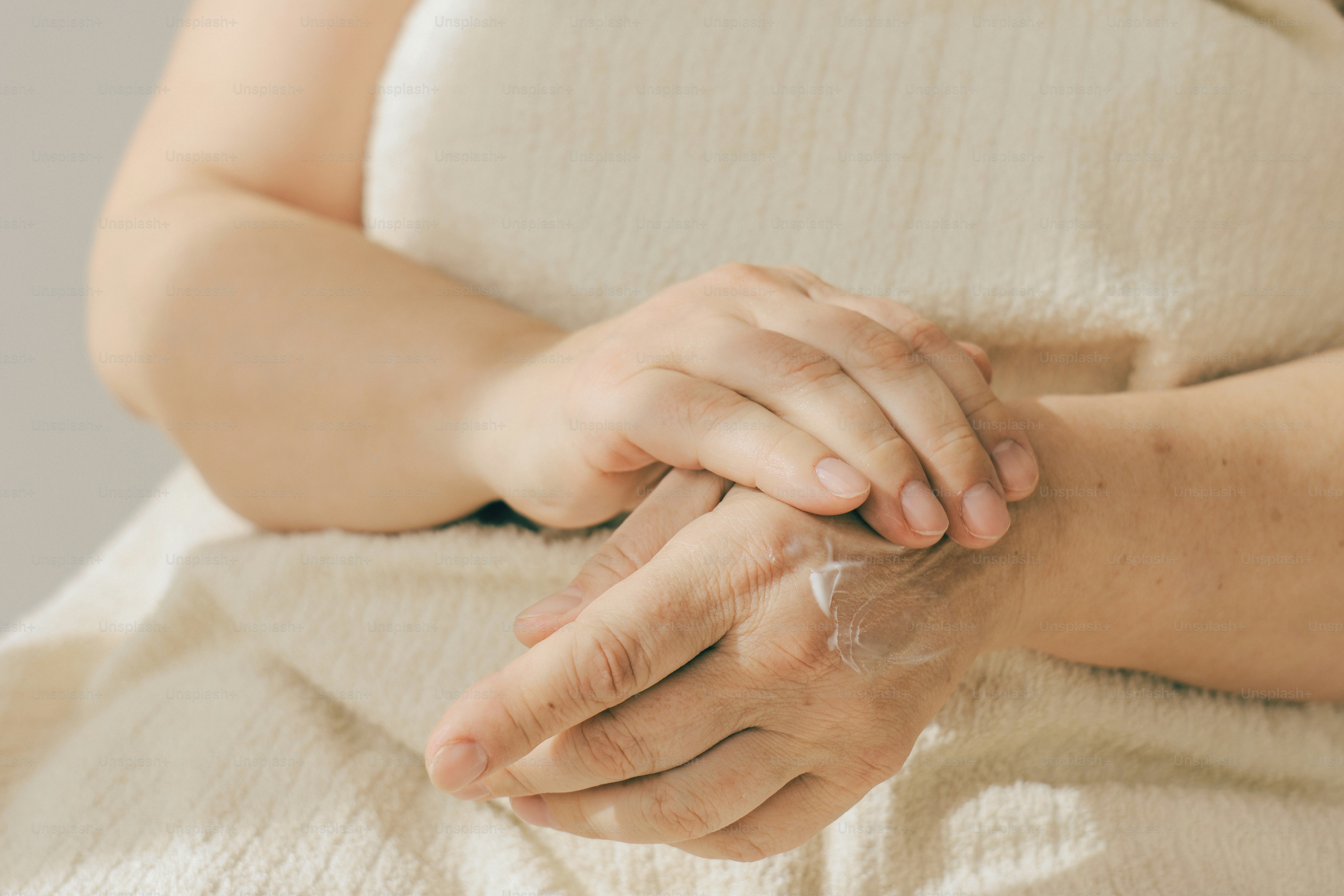 Hands applying moisturizer on dry skin.