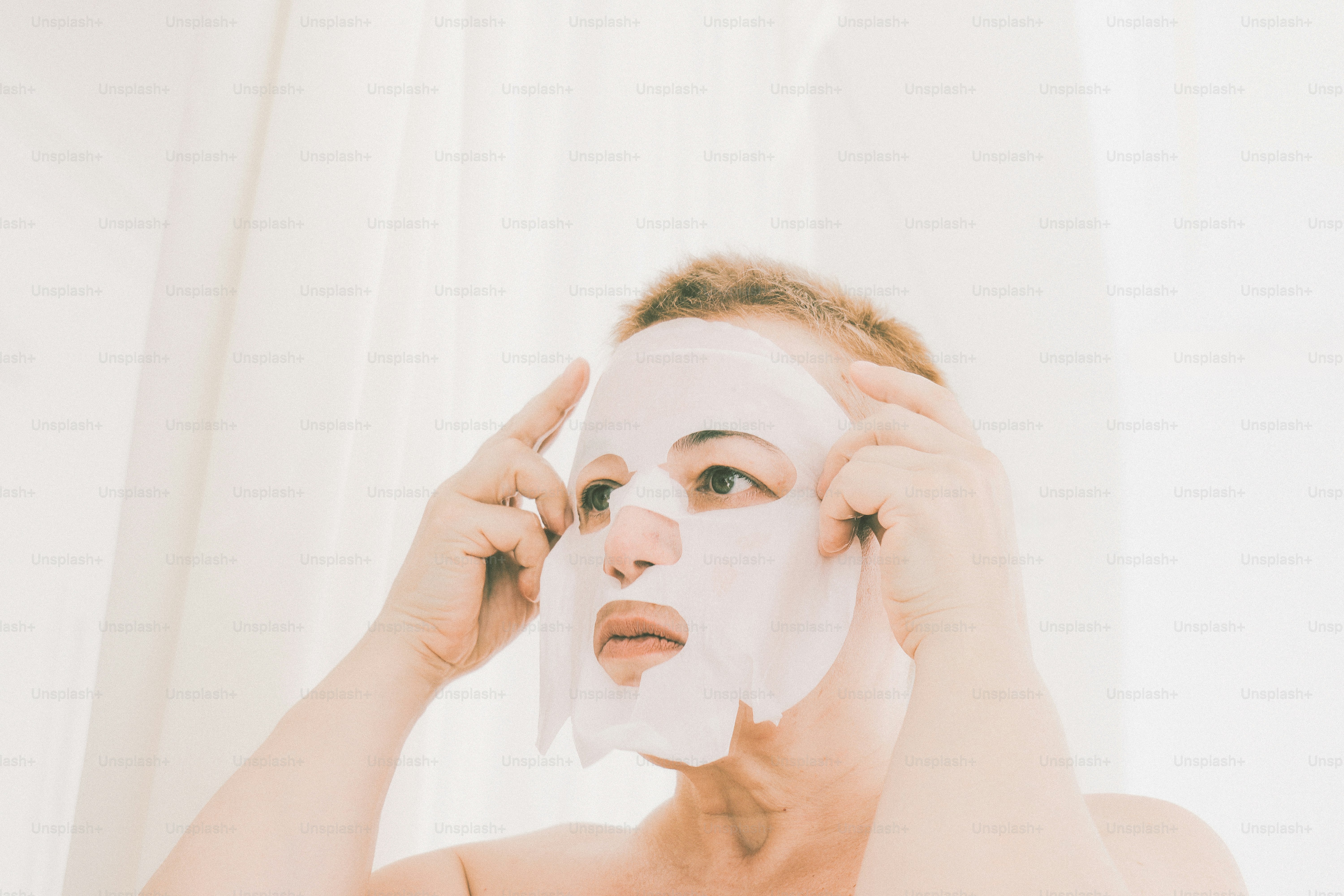 Woman applying a white facial sheet mask