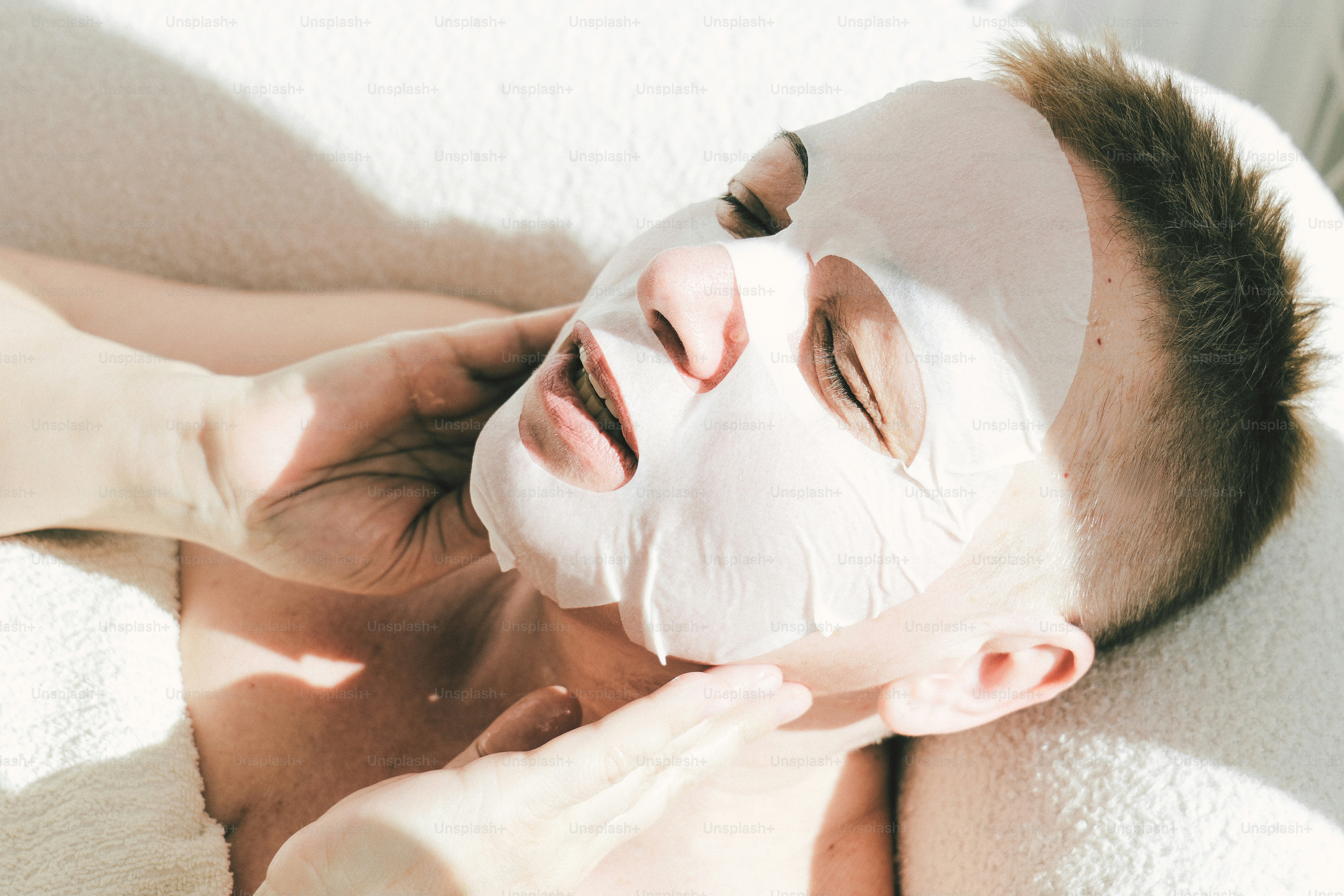 Person with a facial mask relaxing on a white surface