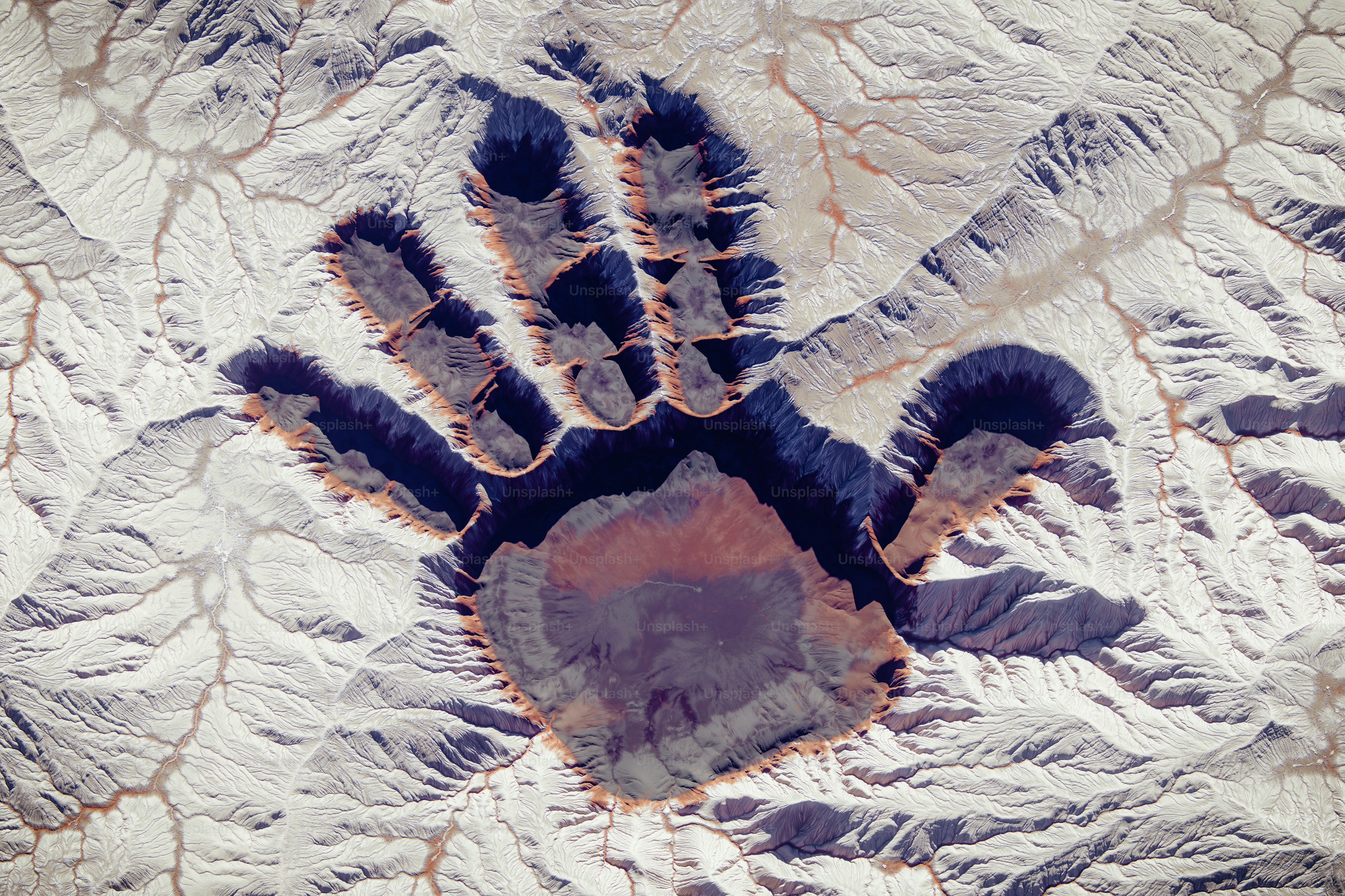 Riesiger Handabdruck, von oben in eine Wüstenlandschaft gemeißelt.