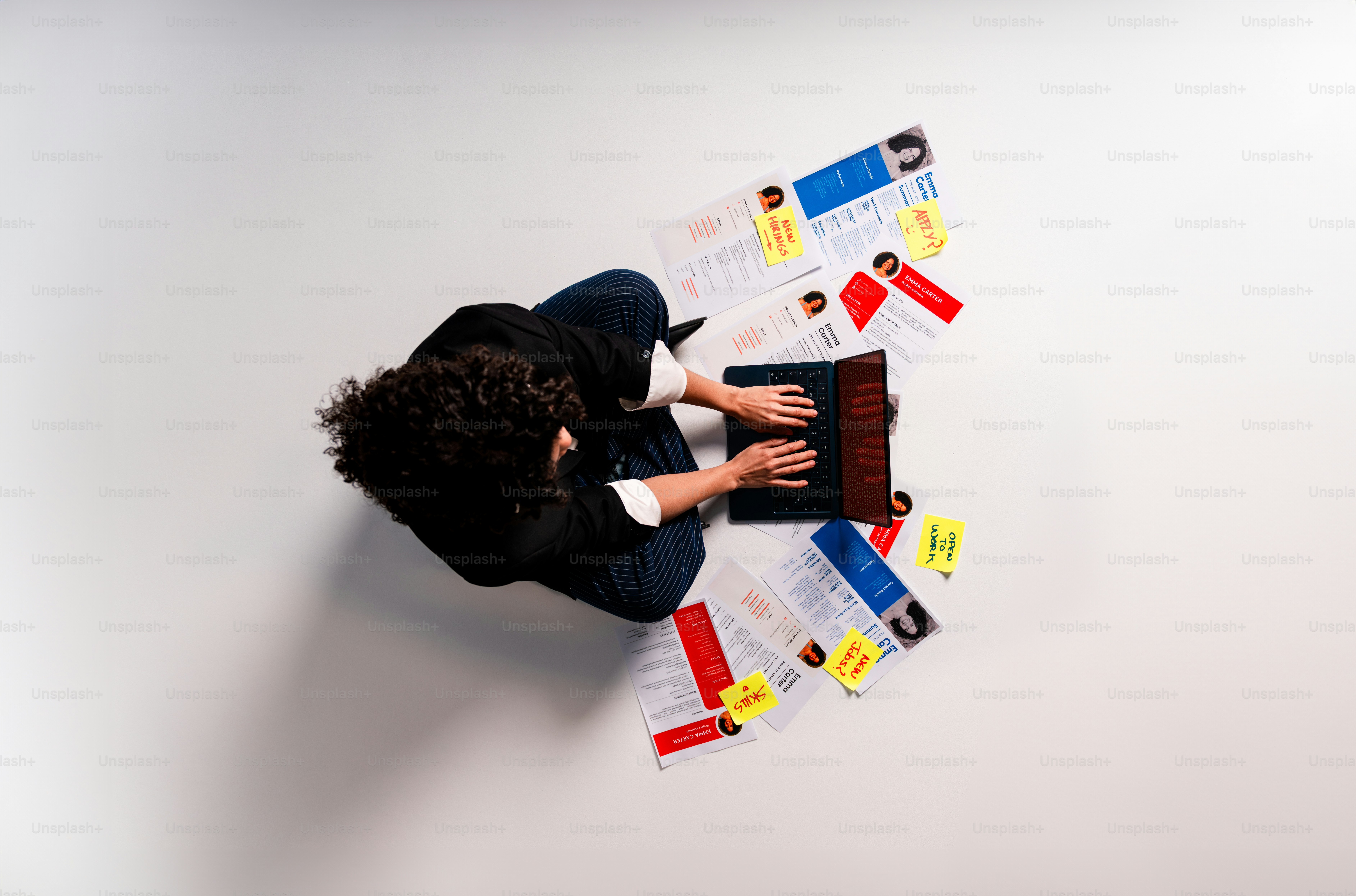 Woman working on laptop surrounded by resumes