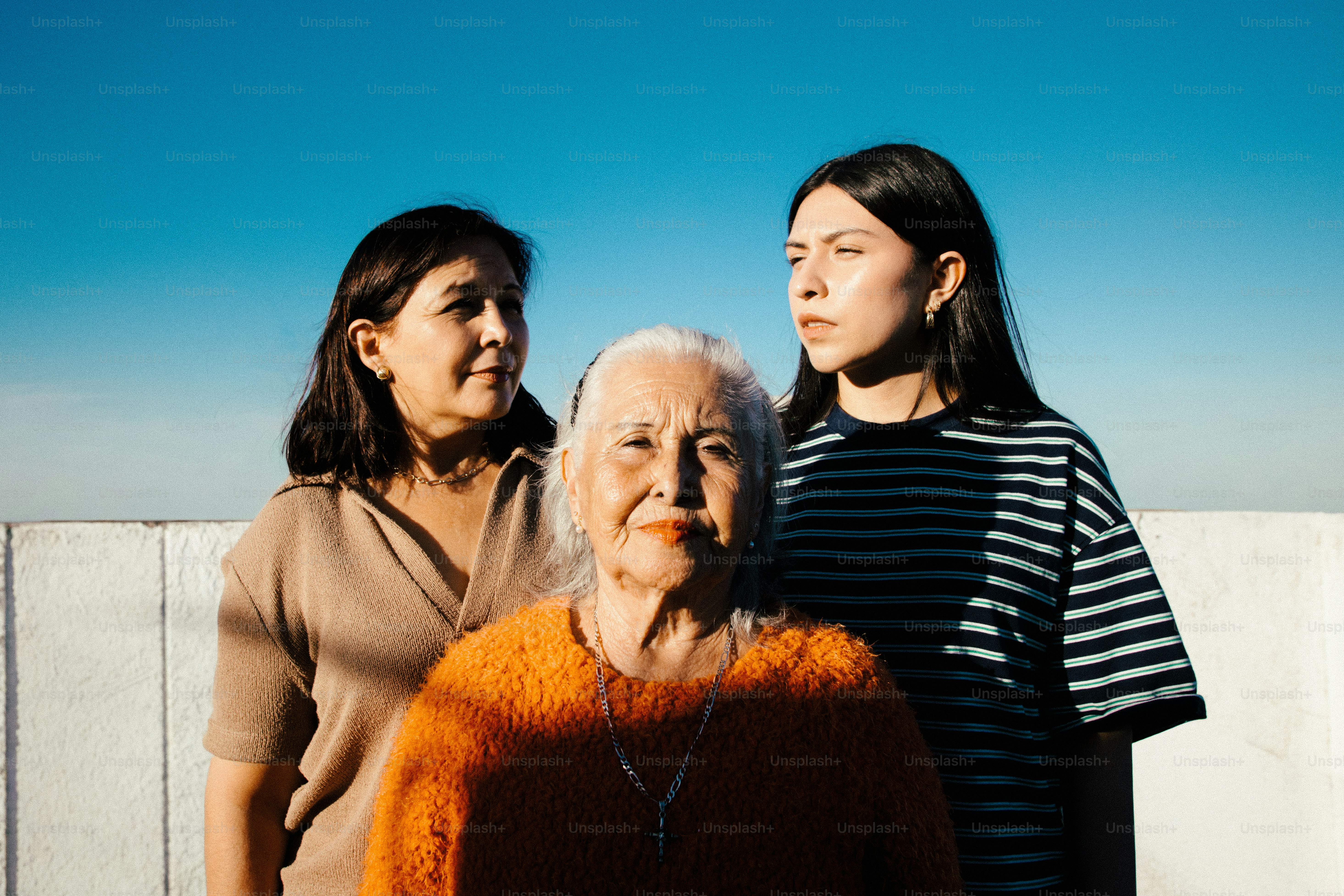 Three women of different generations stand together outdoors. photo ...