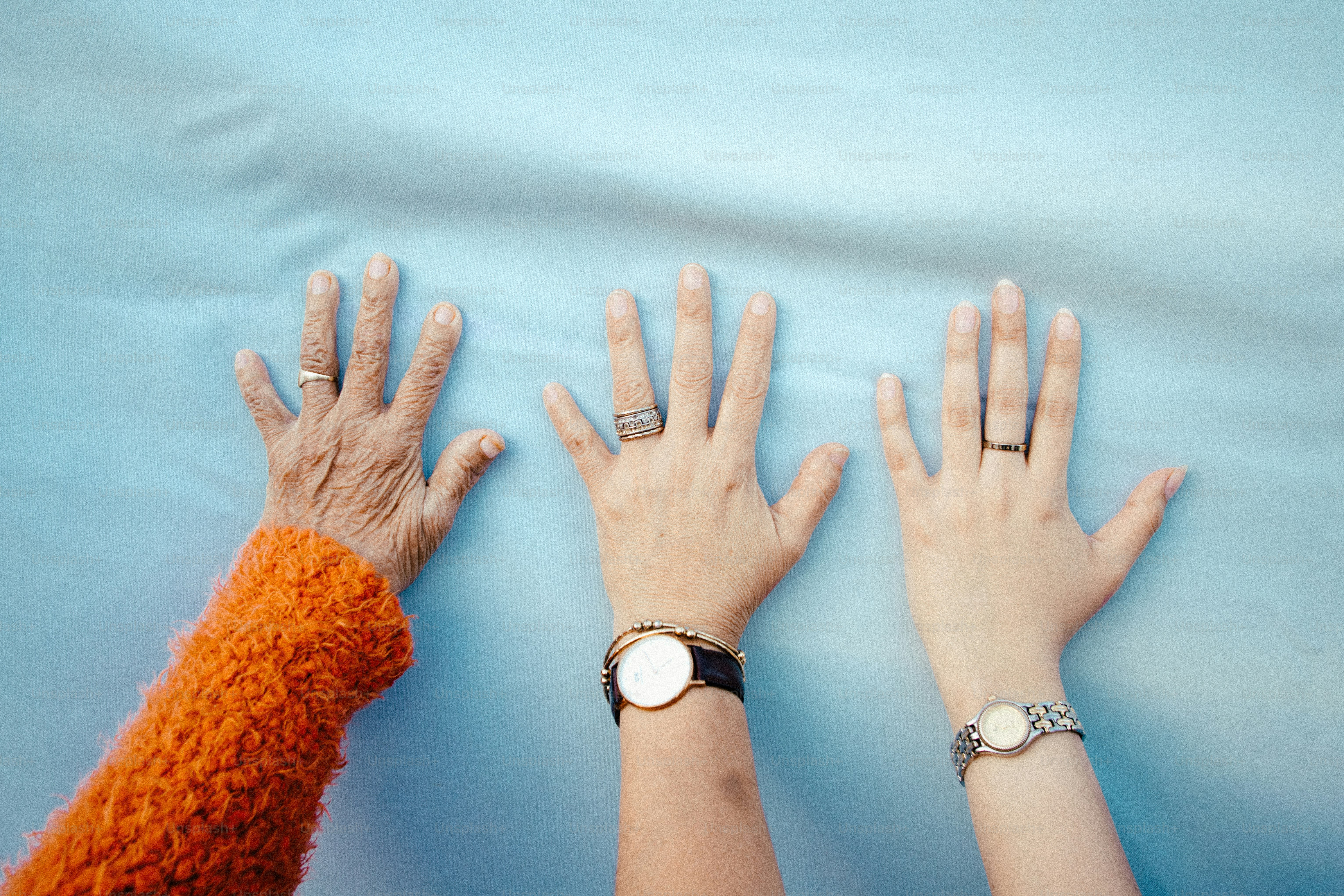 Three hands of different ages reaching up.