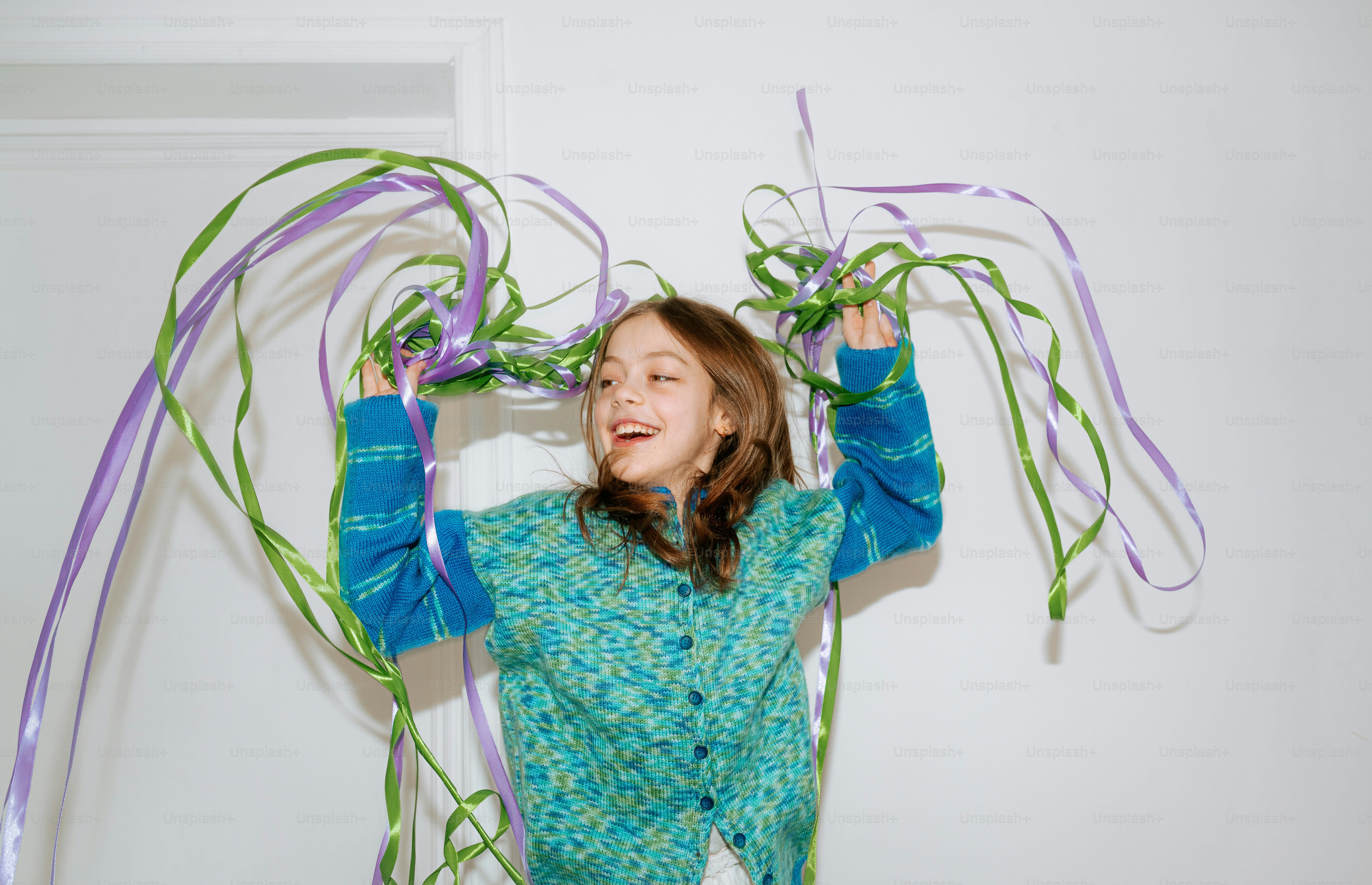 A young girl playing with purple and green streamers