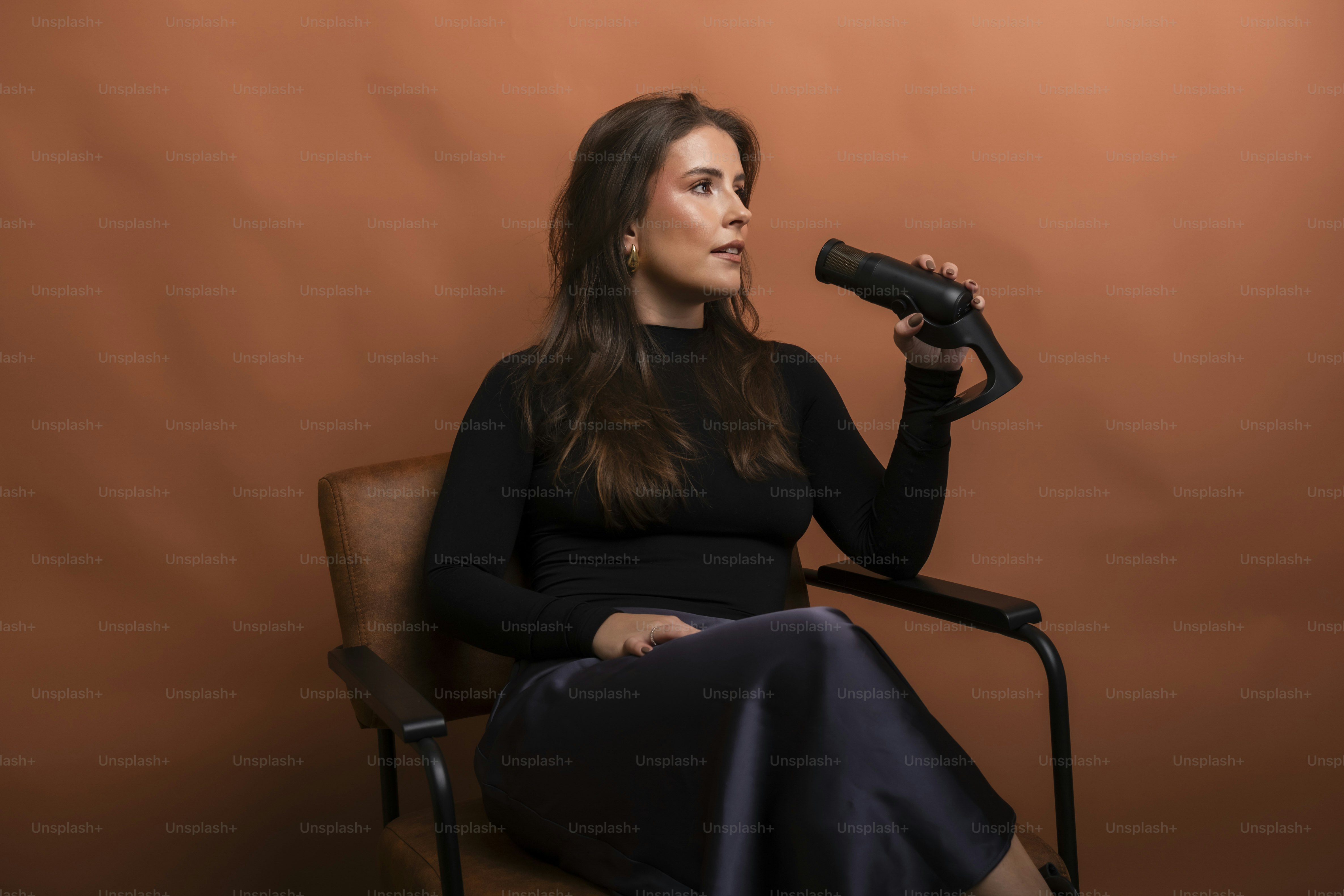 Woman holding a small telescope while sitting in a chair.