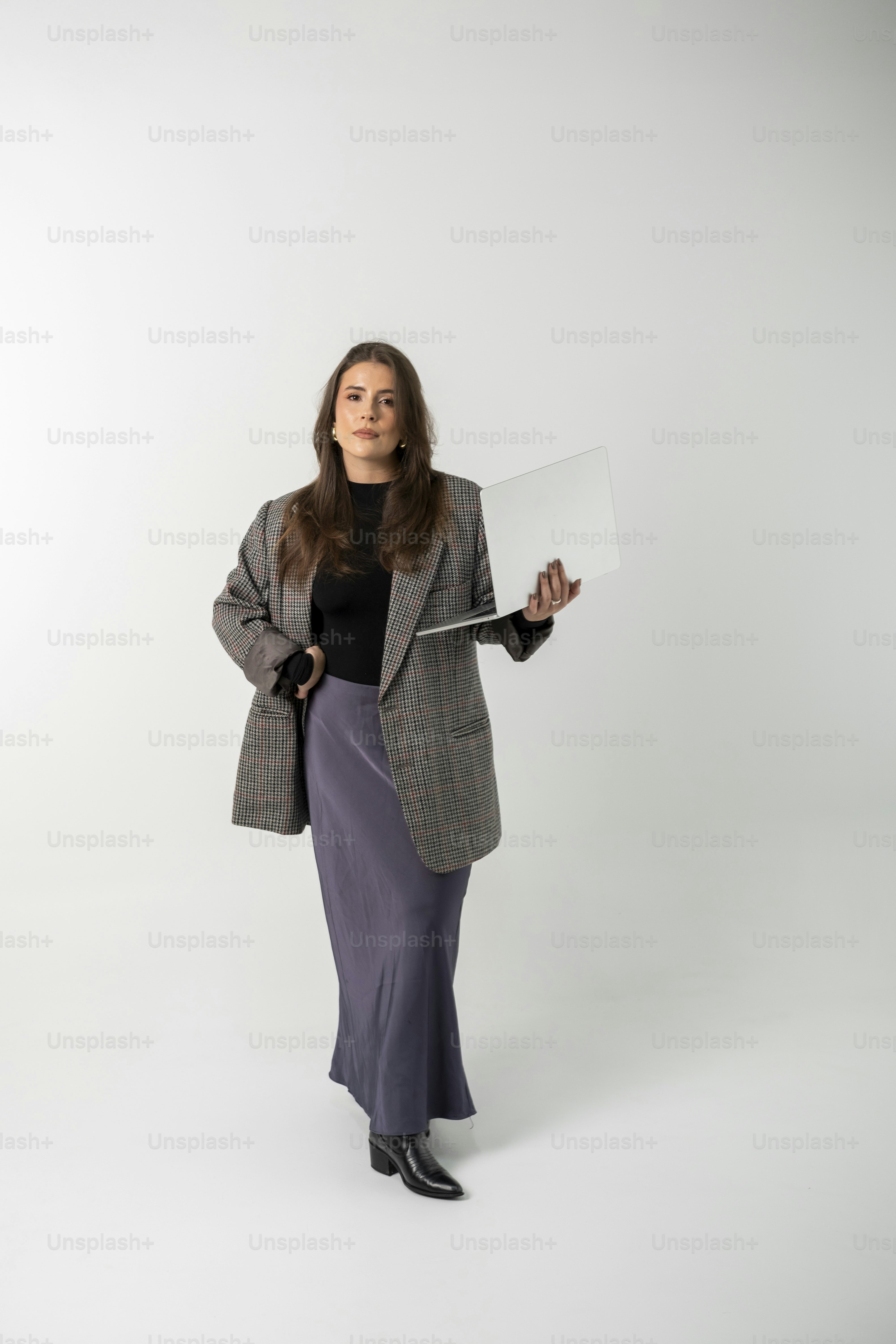 A woman in a blazer holding a laptop