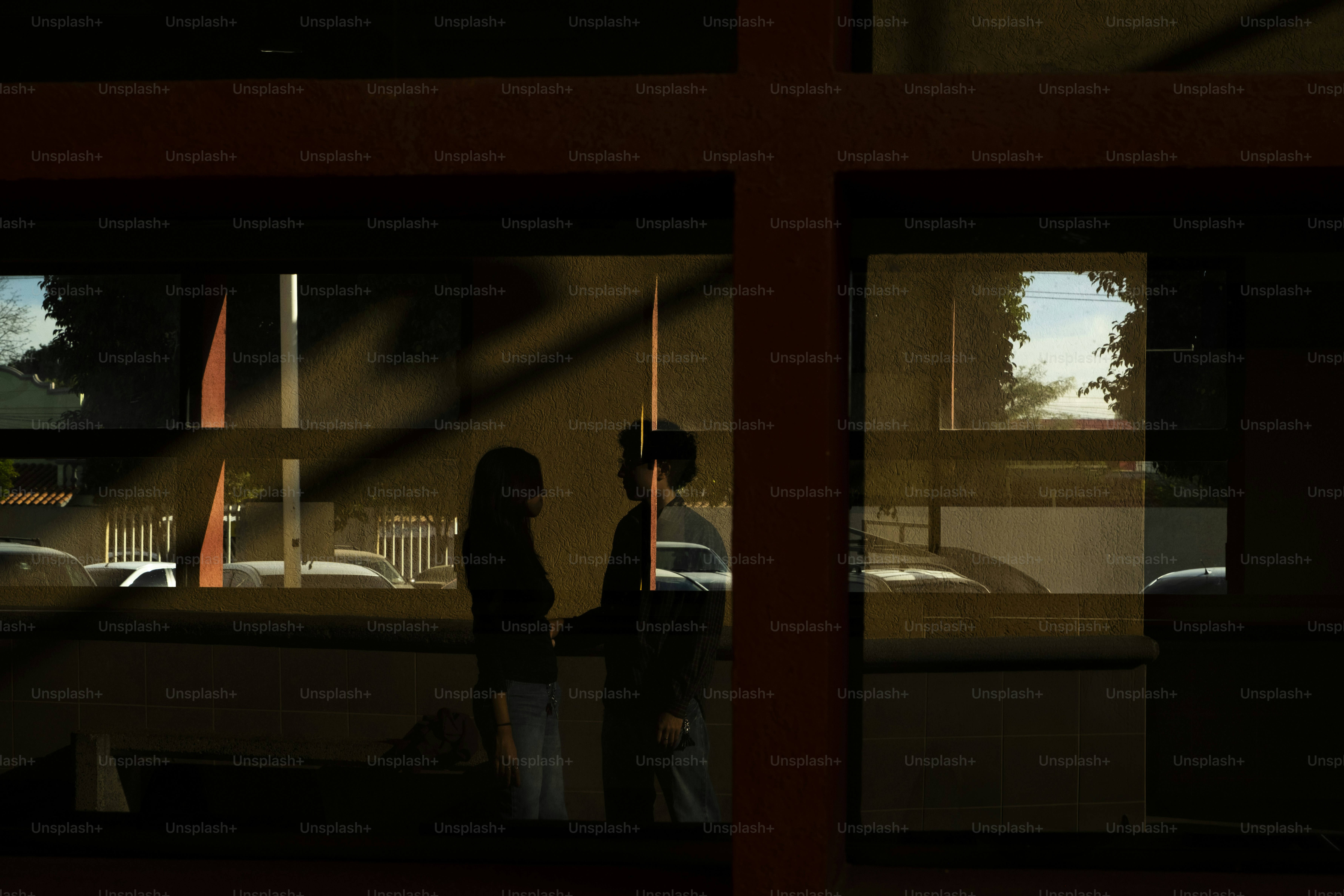 Silhouettes of two people standing near a window.