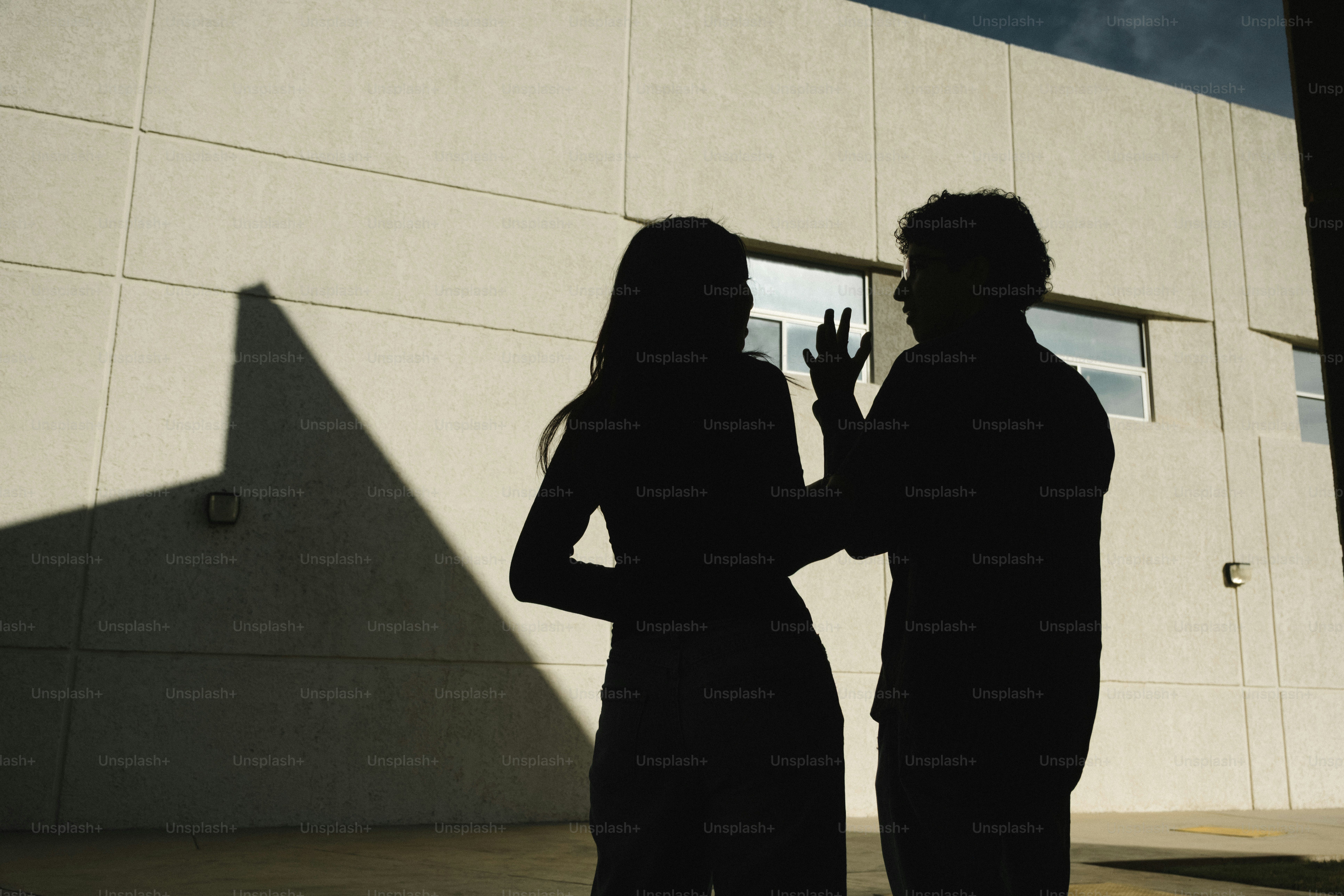 Two people silhouetted against a building