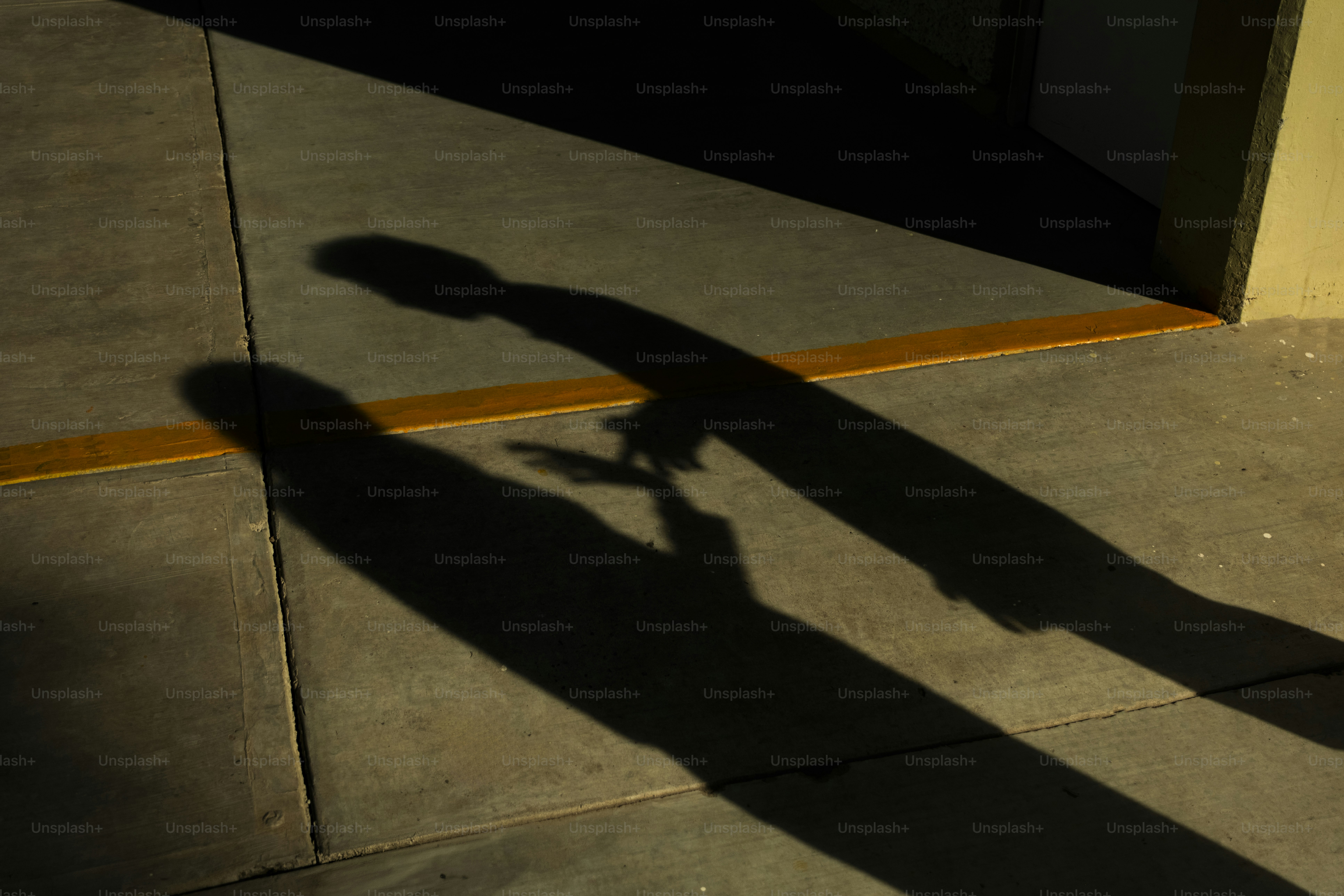 Two shadows cast on a concrete floor