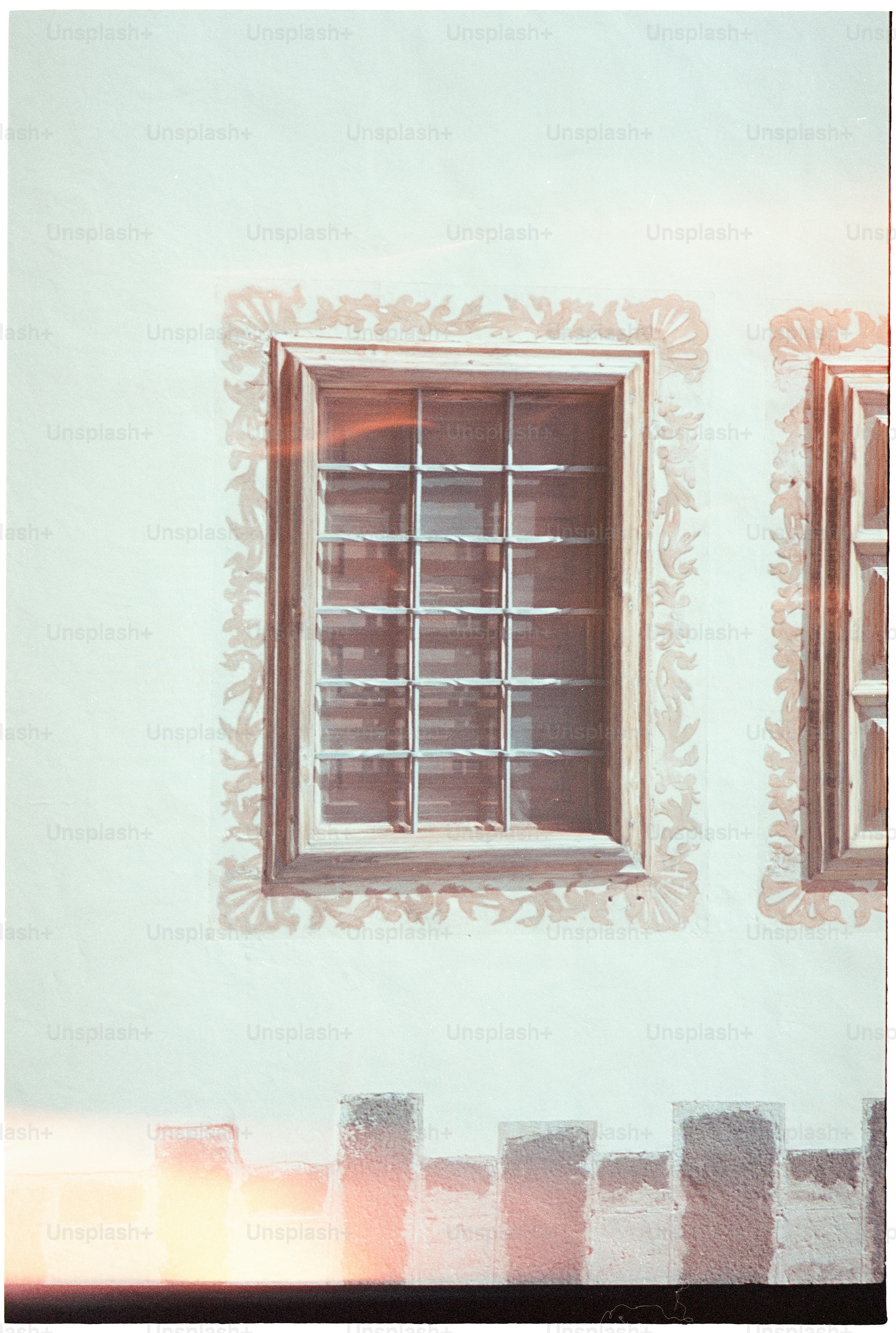 A white wall with a decorated window and fence