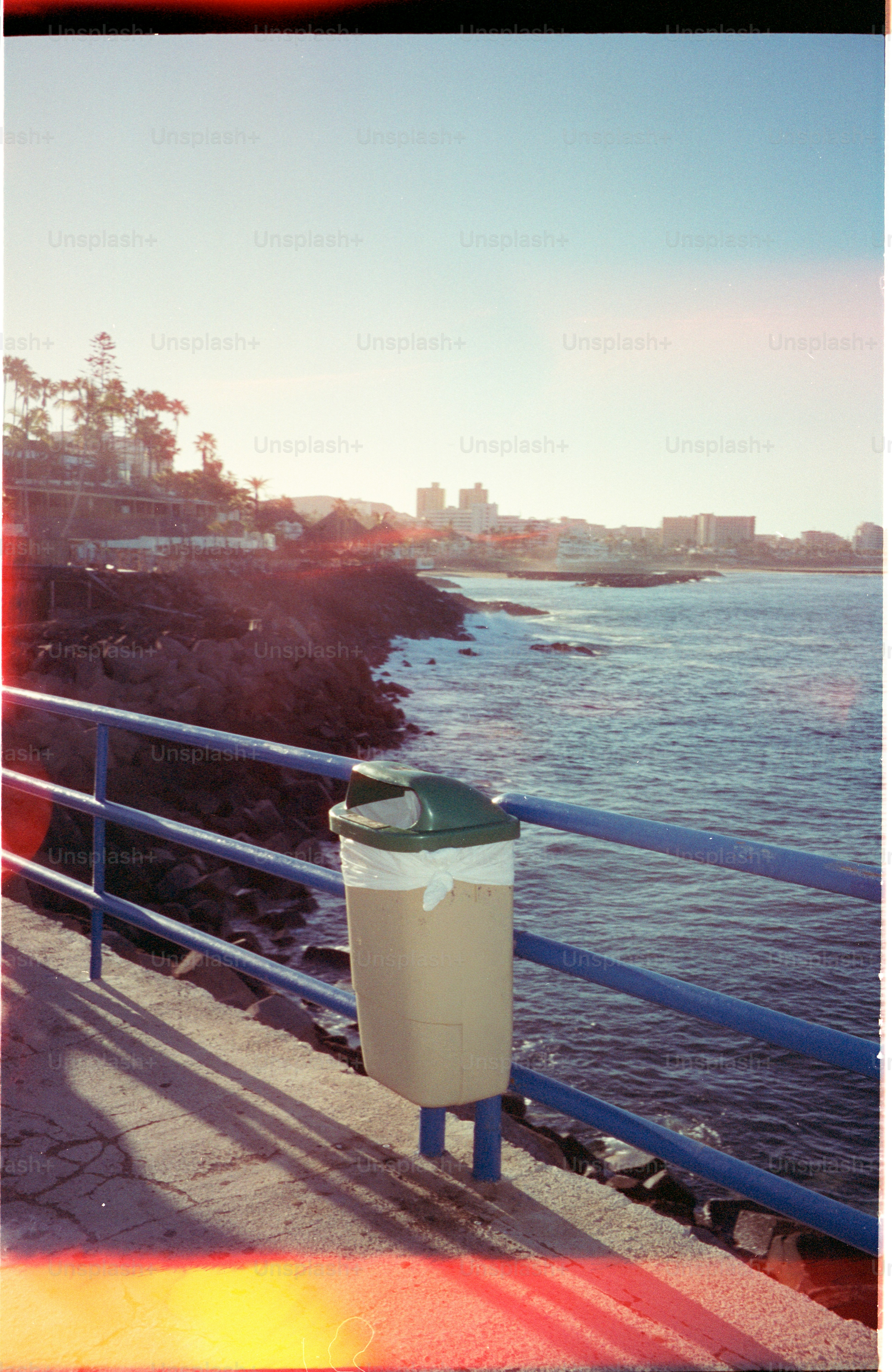 Cestino della spazzatura su un molo che domina l'oceano e la città.