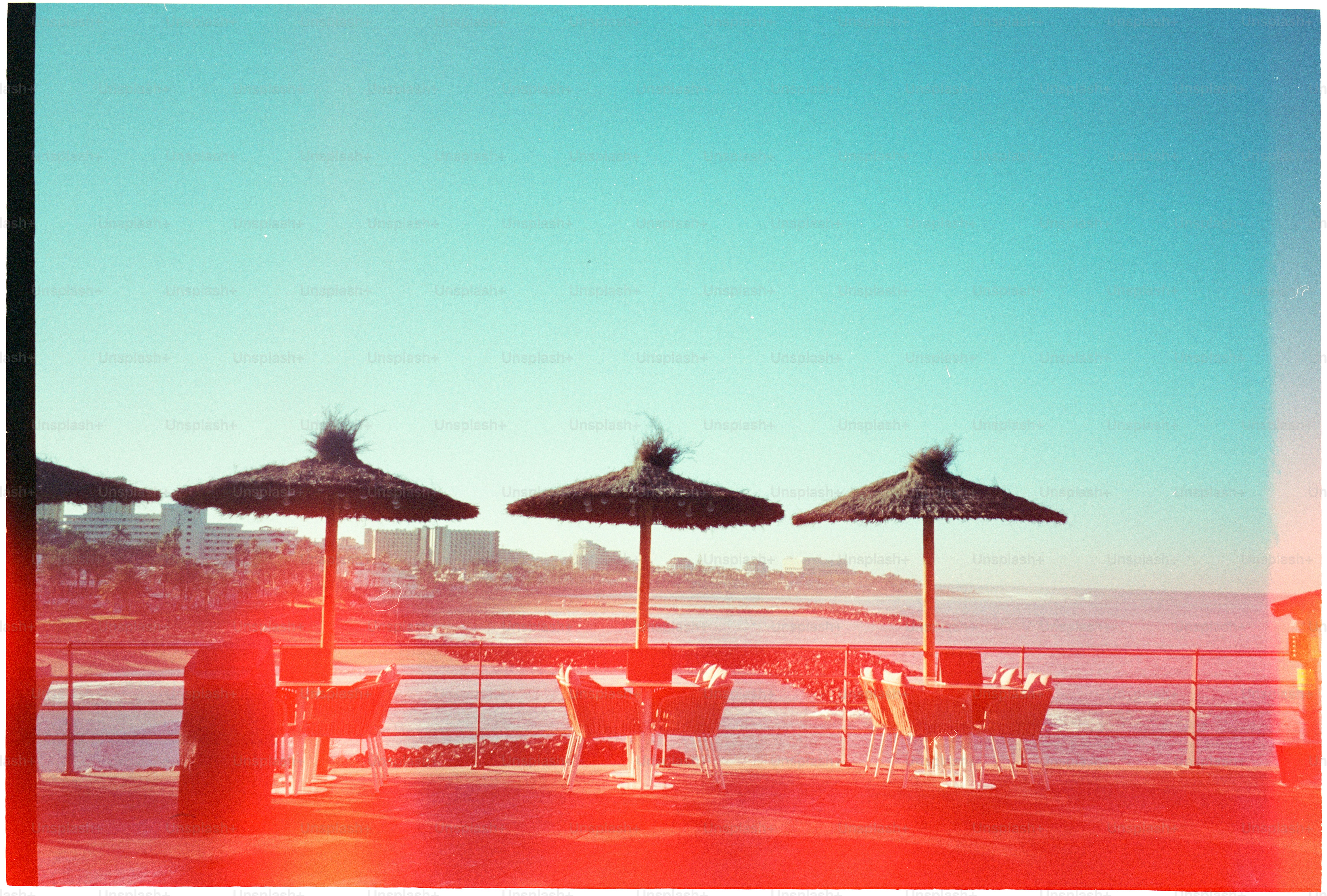 Beachside cafe with umbrellas and tables overlooking ocean.