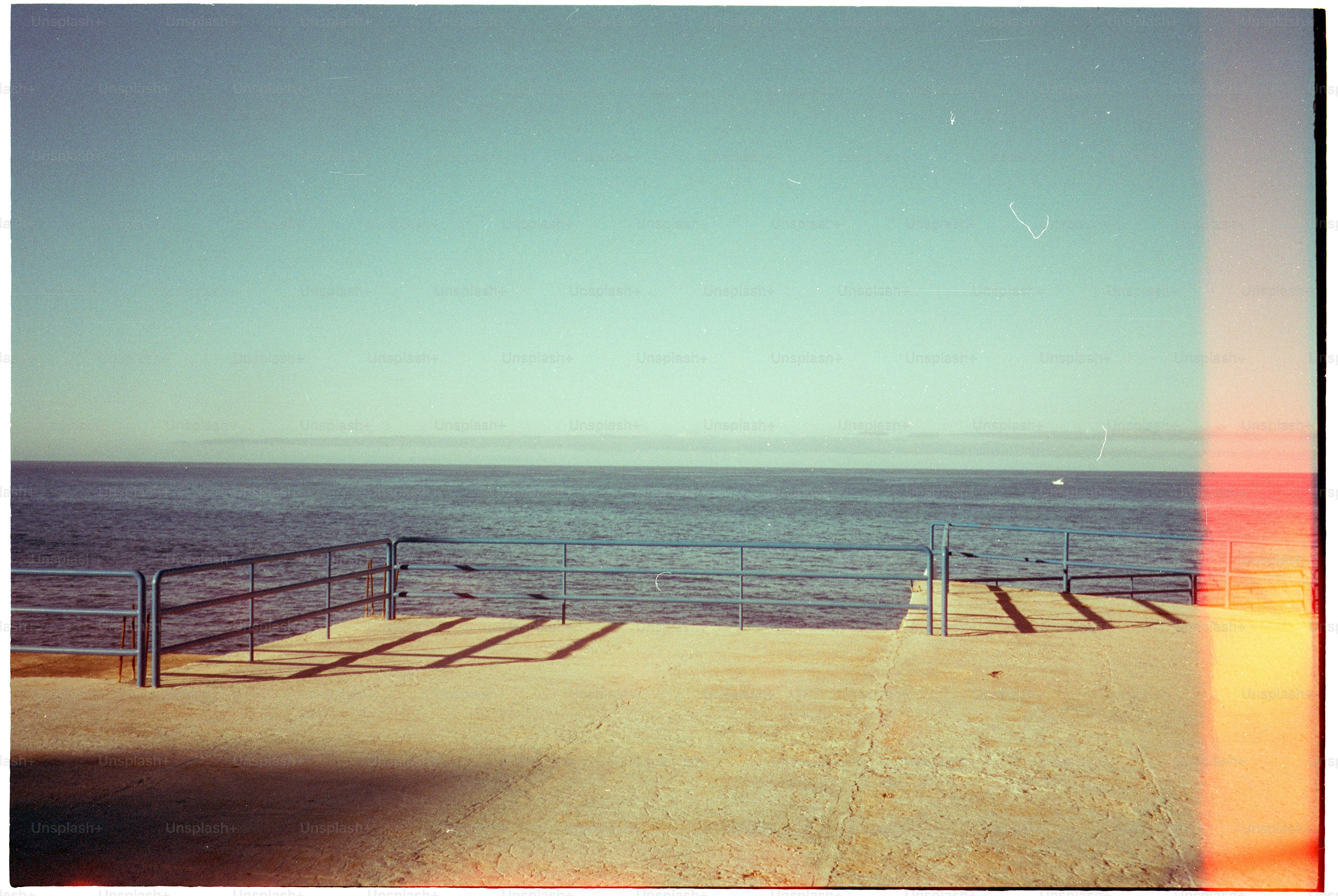 Vialetto in cemento con ringhiera che si affaccia su un calmo oceano blu