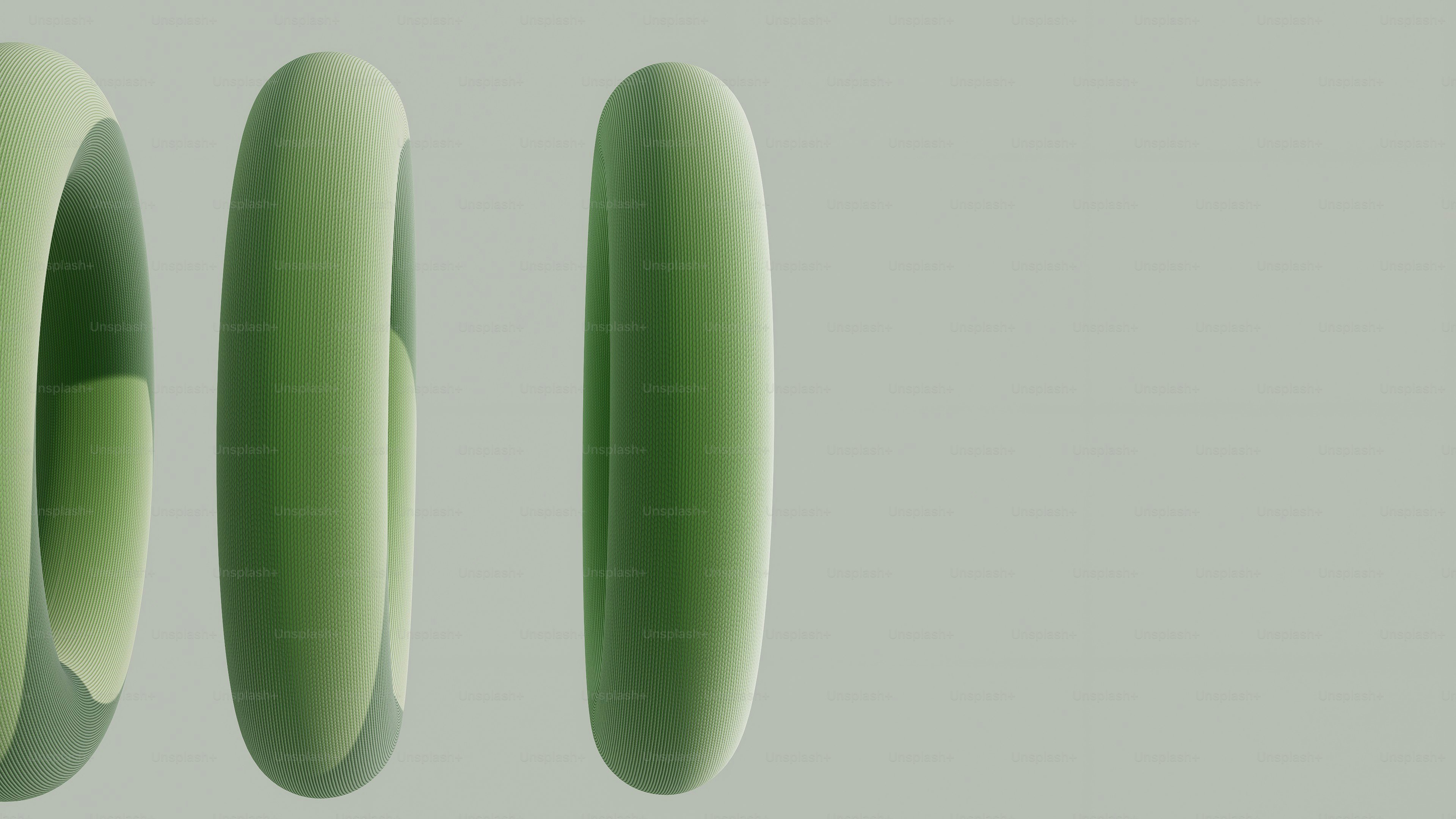 Three green torus shapes on a light gray background