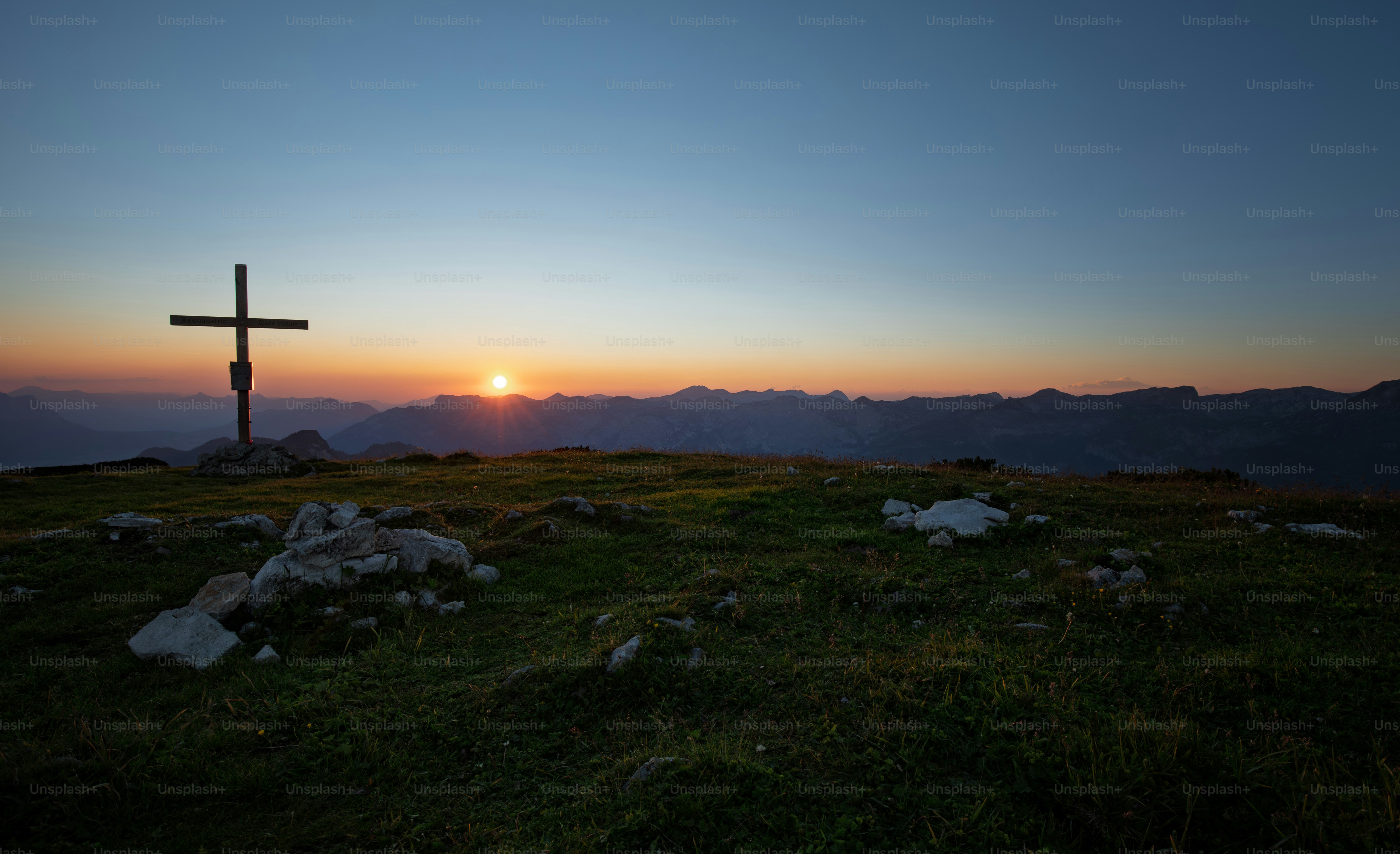 Cross on mountain summit at sunrise with clear sky